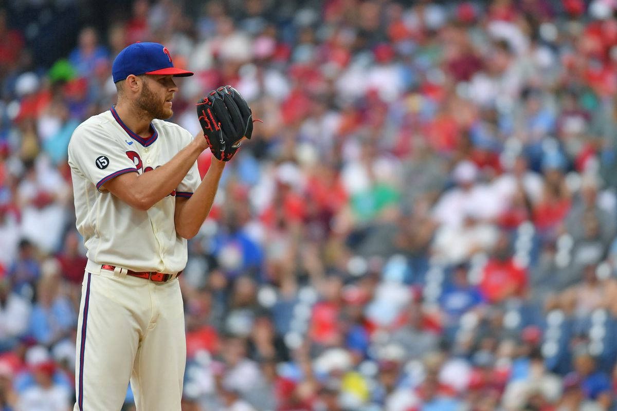 Phillies 桌布 壁紙 — 一位身穿白色制服、戴藍色帽子的棒球投手站在投手丘上，比賽中將手套貼在胸前，背景是模糊的人群。