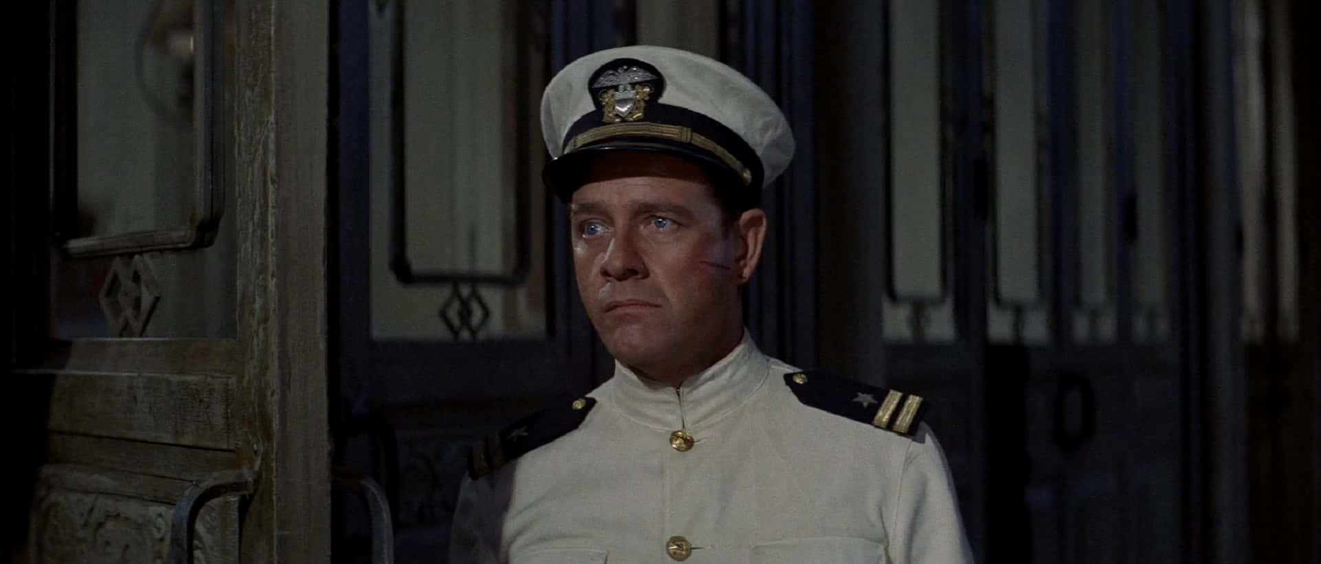 Richard Crenna 桌布 壁紙 — 一位身穿白色制服、配有金色鈕扣和肩章的海軍軍官，站在一個光線昏暗的房間裡，身後是華麗的木門。