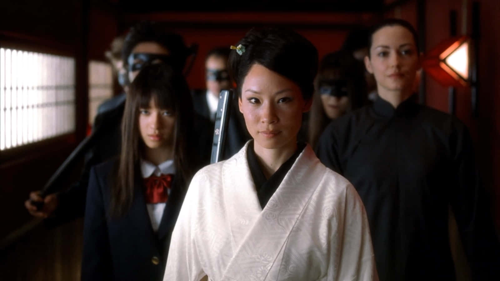 lucy liu 桌布 壁紙 — 一位身穿白色和服的女性站在畫面中央，腰間佩帶武士刀，兩旁有戴面具的人物，身處燈光昏暗的傳統日本走廊。