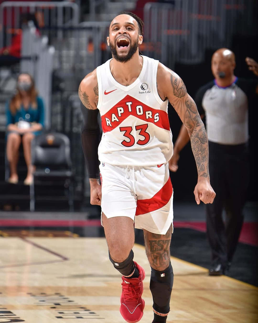 NBA 桌布 壁紙 — 一位身穿白色和紅色球衣的多倫多暴龍籃球運動員在硬木球場上高舉雙臂慶祝。