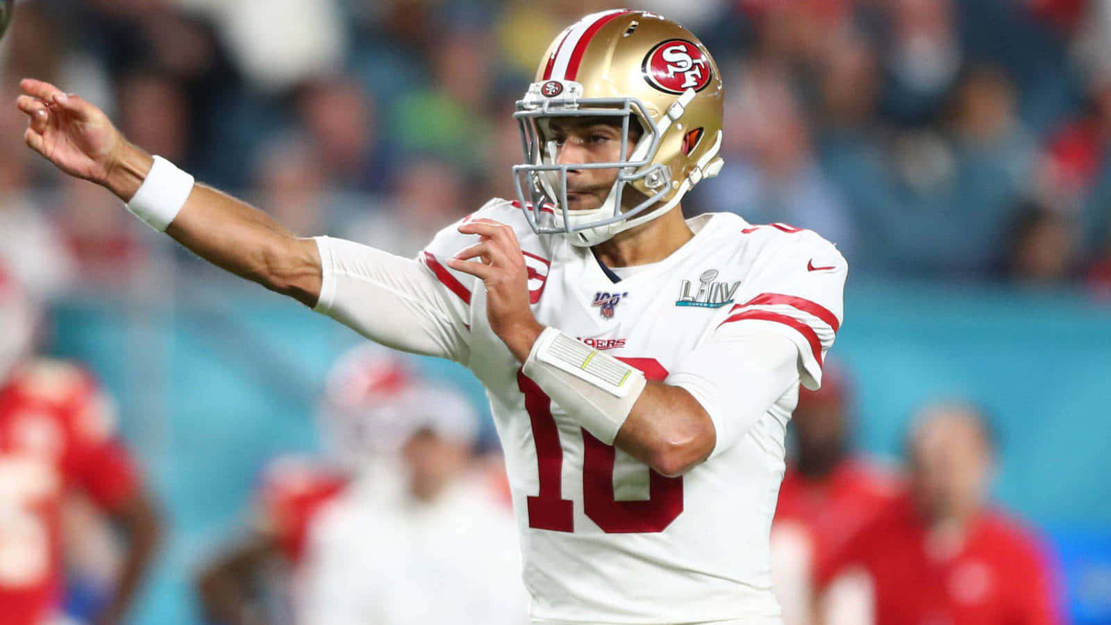 Joe Montana 桌布 壁紙 — 一位身穿白色和紅色球衣的舊金山四九人四分衛在夜間比賽中於球場燈光下投擲橄欖球。