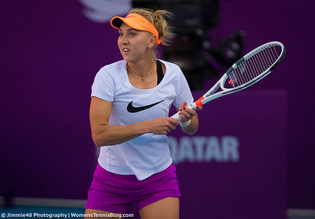 Tennis 桌布 壁紙 — 一位身穿白色和紫色裝備的女網球運動員，在充滿活力的紫色球場背景下，全神貫注地揮動球拍。