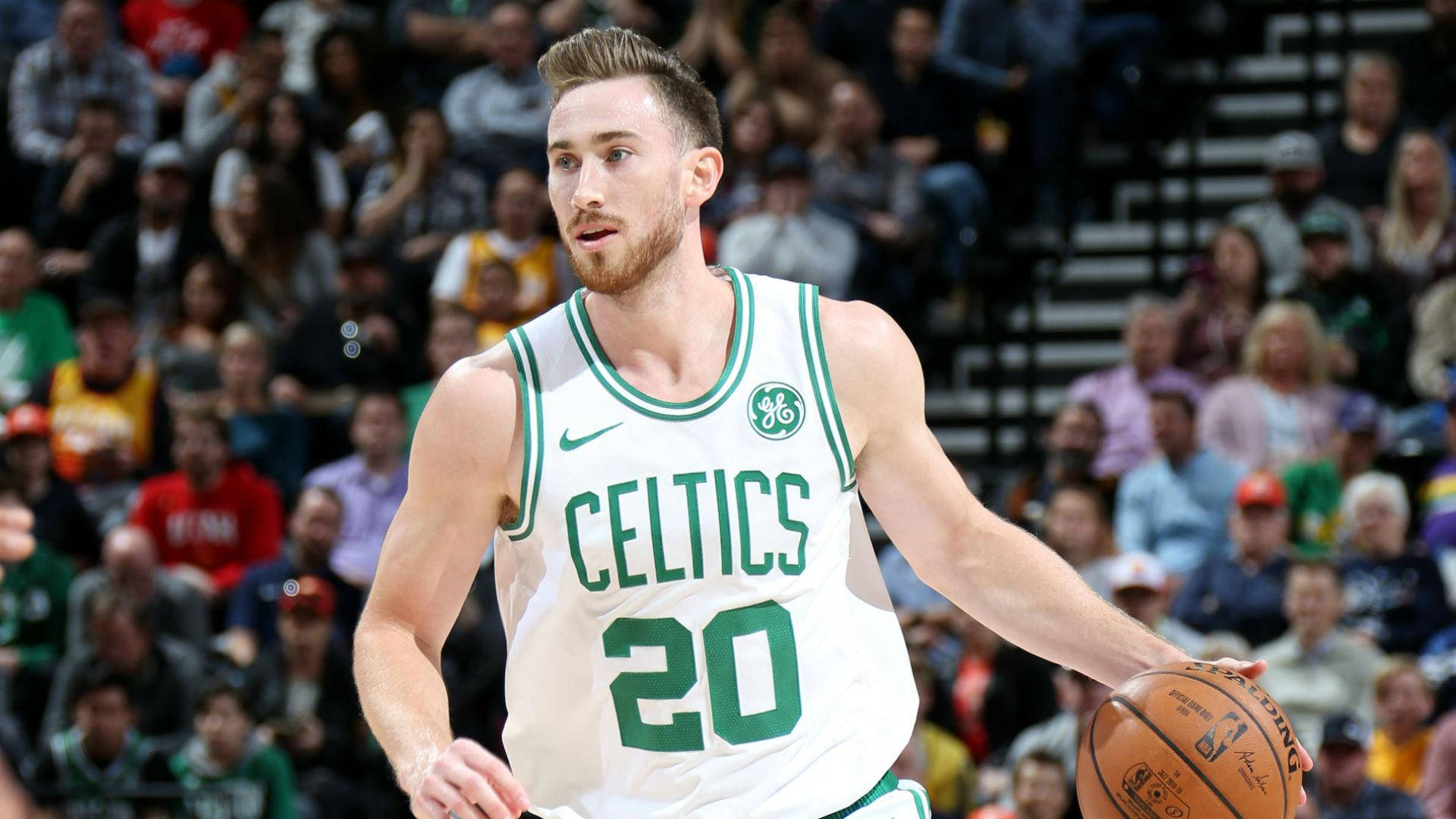 gordon hayward 桌布 壁紙 — 一位身穿白色和綠色球衣的波士頓塞爾提克籃球運動員在比賽中運球，背景是模糊的人群。
