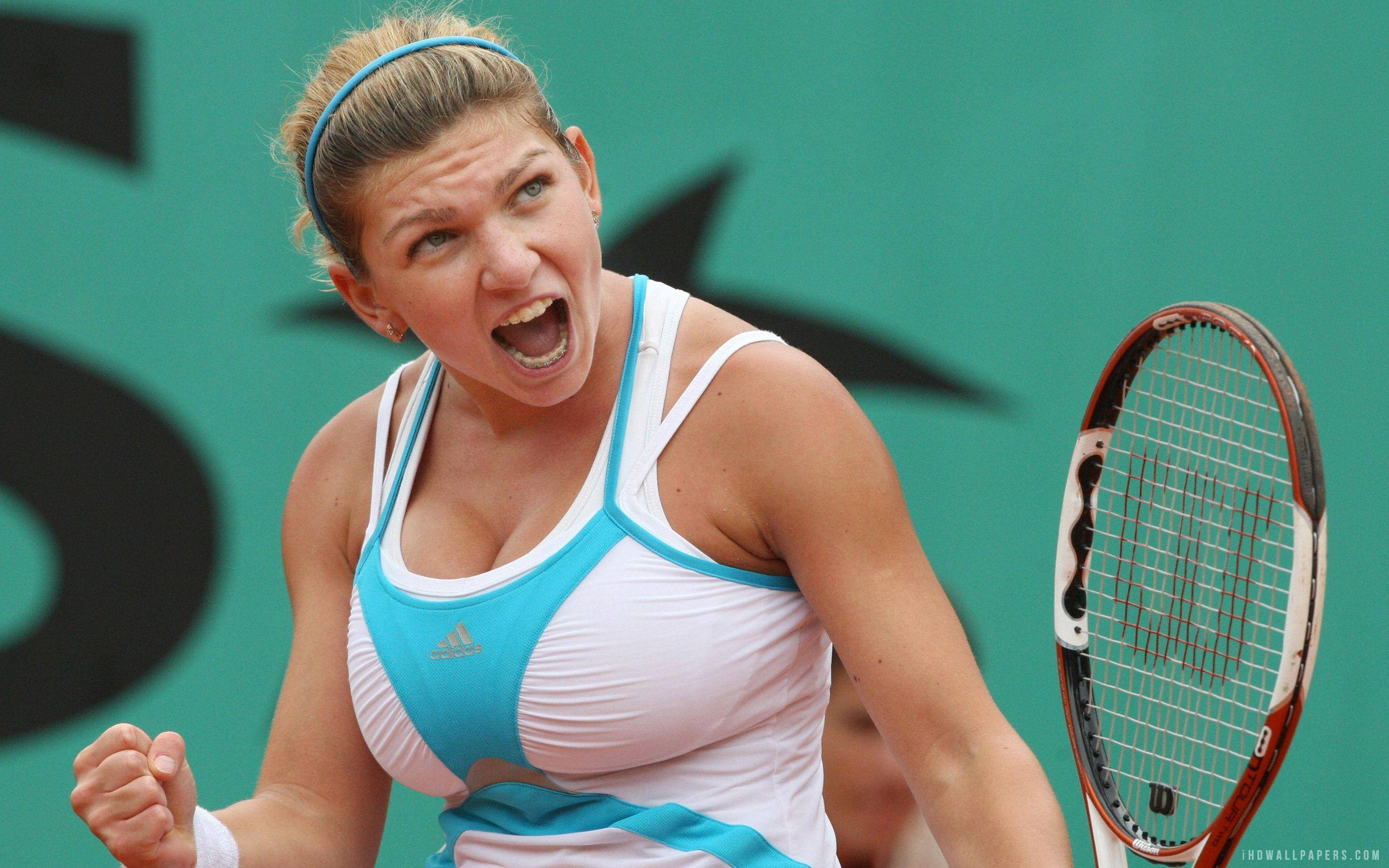 Simona Halep 桌布 壁紙 — 一位身穿白色和藍色服裝的女網球運動員在紅土球場上握緊球拍，發出勝利的吼叫。