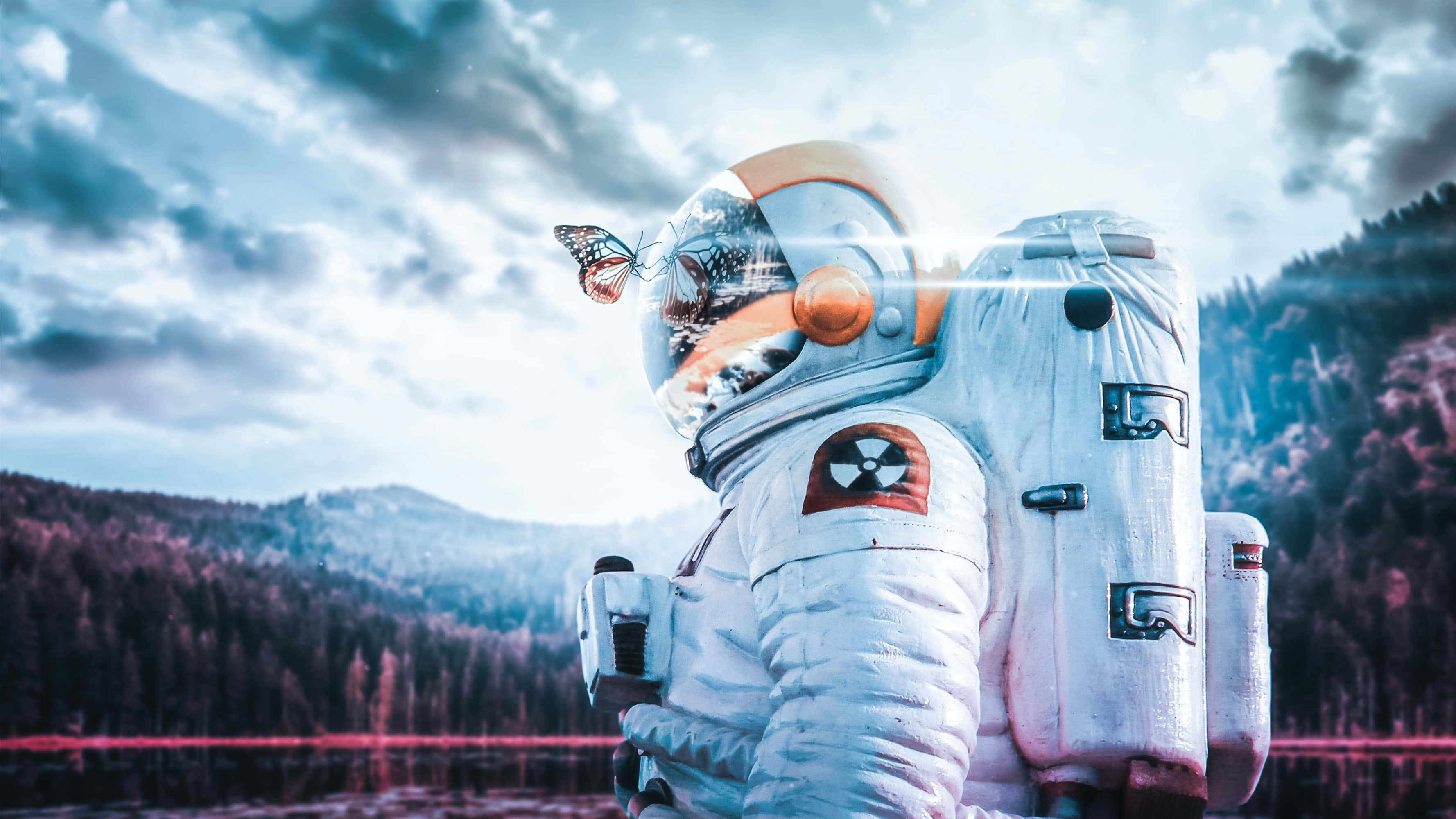 Amazing Astronaut 桌布 壁紙 — 一位身穿白色太空衣的太空人站在湖邊，背後有山脈，頭盔上停著一隻蝴蝶。