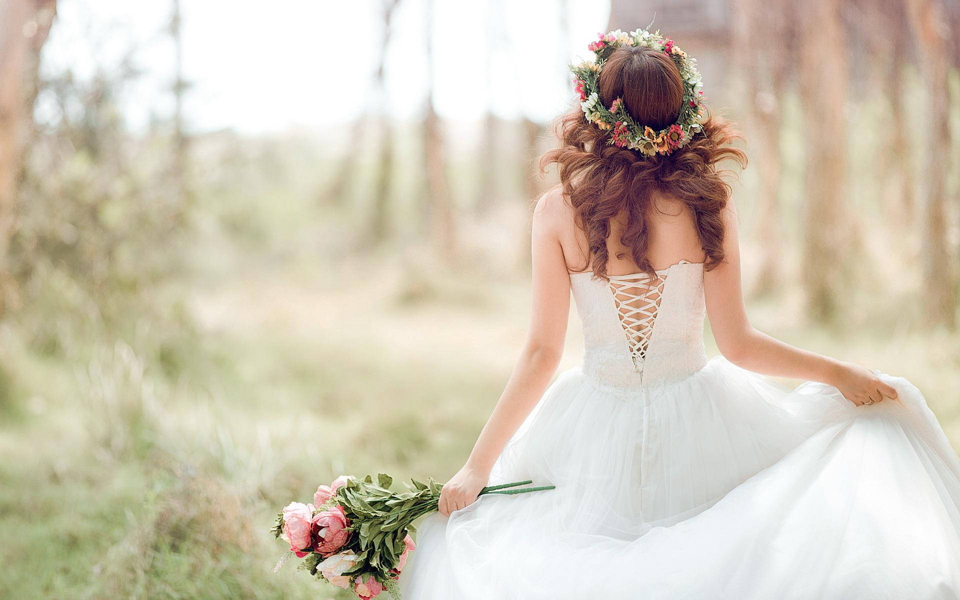 Bride 桌布 壁紙 — 一位身穿白色婚紗、頭戴花冠的新娘，在陽光明媚的森林中漫步，手持一束粉紅玫瑰。
