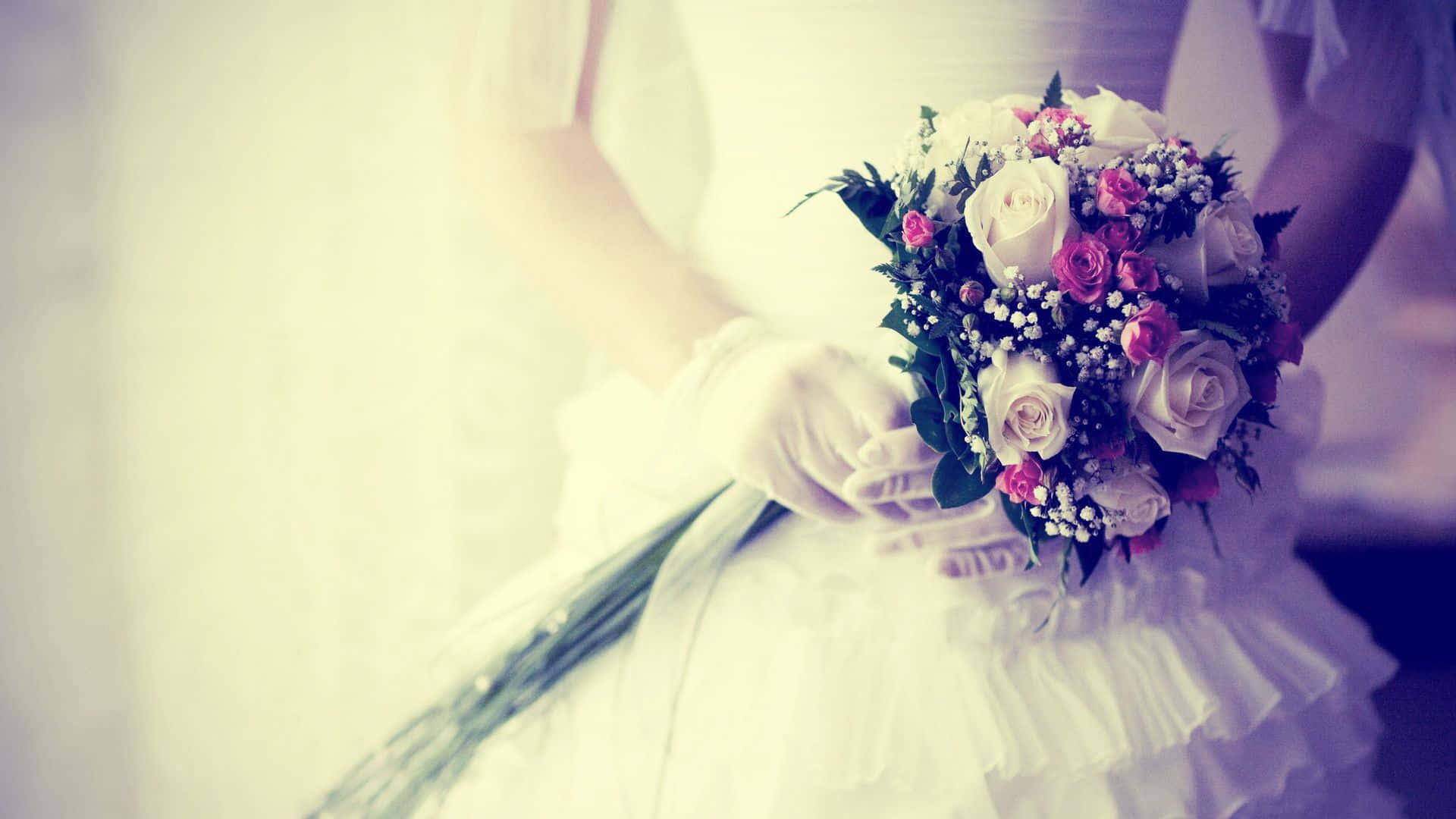 Bride 桌布 壁紙 — 一位身穿白色婚紗和手套的新娘，在柔和模糊的背景前，手持一束粉紅和白色玫瑰搭配綠葉的花束。