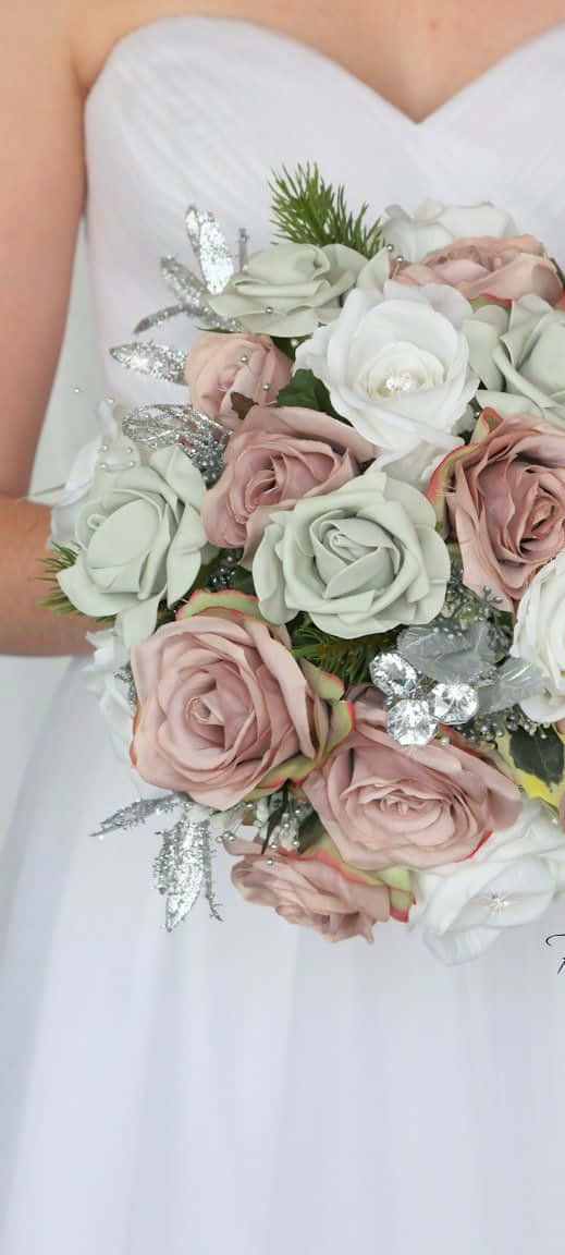Roses Wedding 桌布 壁紙 — 一位身穿白色婚紗的新娘手持一束豐滿的淡粉紅色和鼠尾草綠色玫瑰，點綴著銀色亮粉葉子和松針。