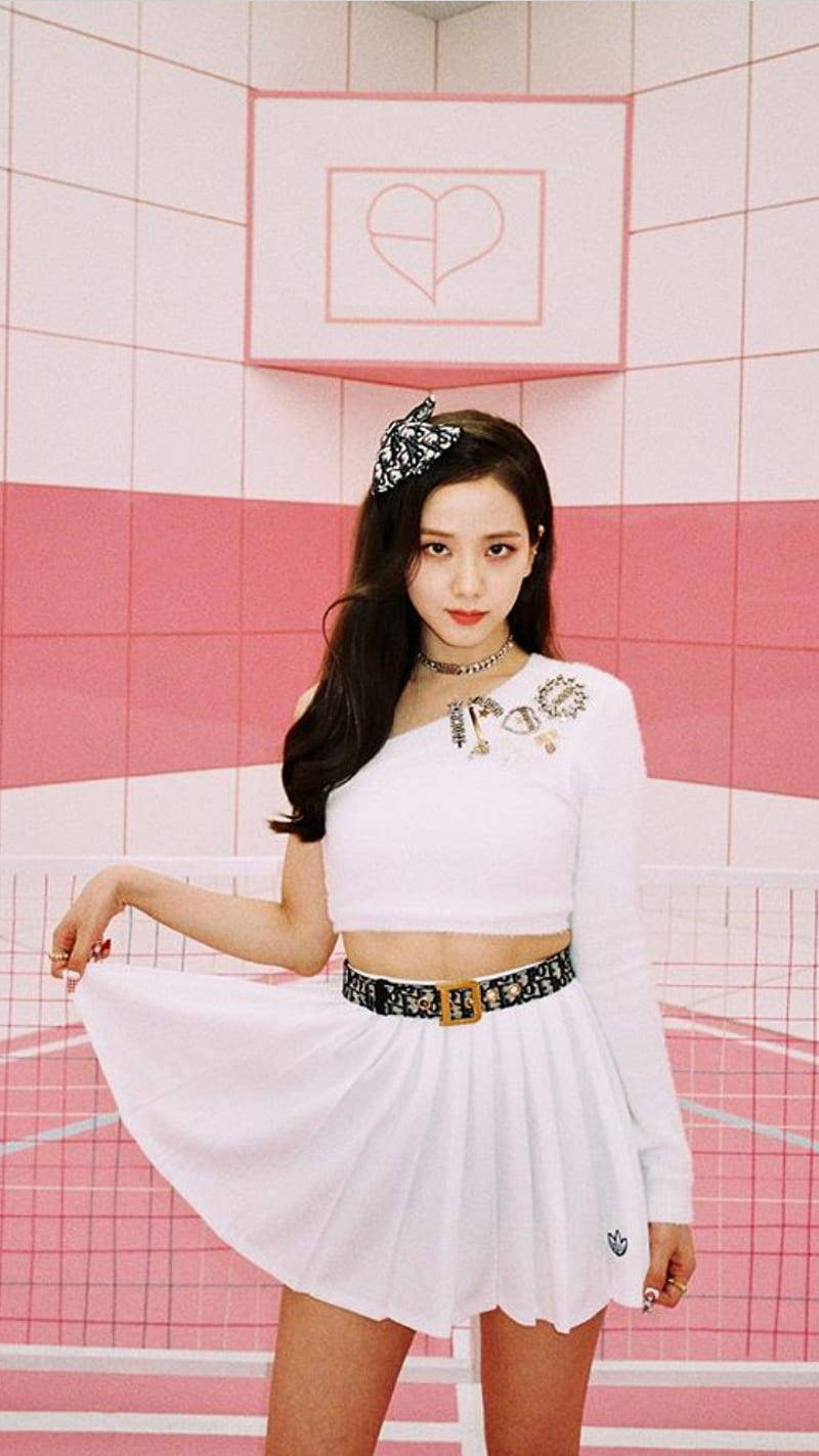 Jisoo Cute 桌布 壁紙 — 一位身穿白色服裝的年輕女子在粉紅色和白色瓷磚牆前自信地擺姿勢，牆上有一個心形符號。