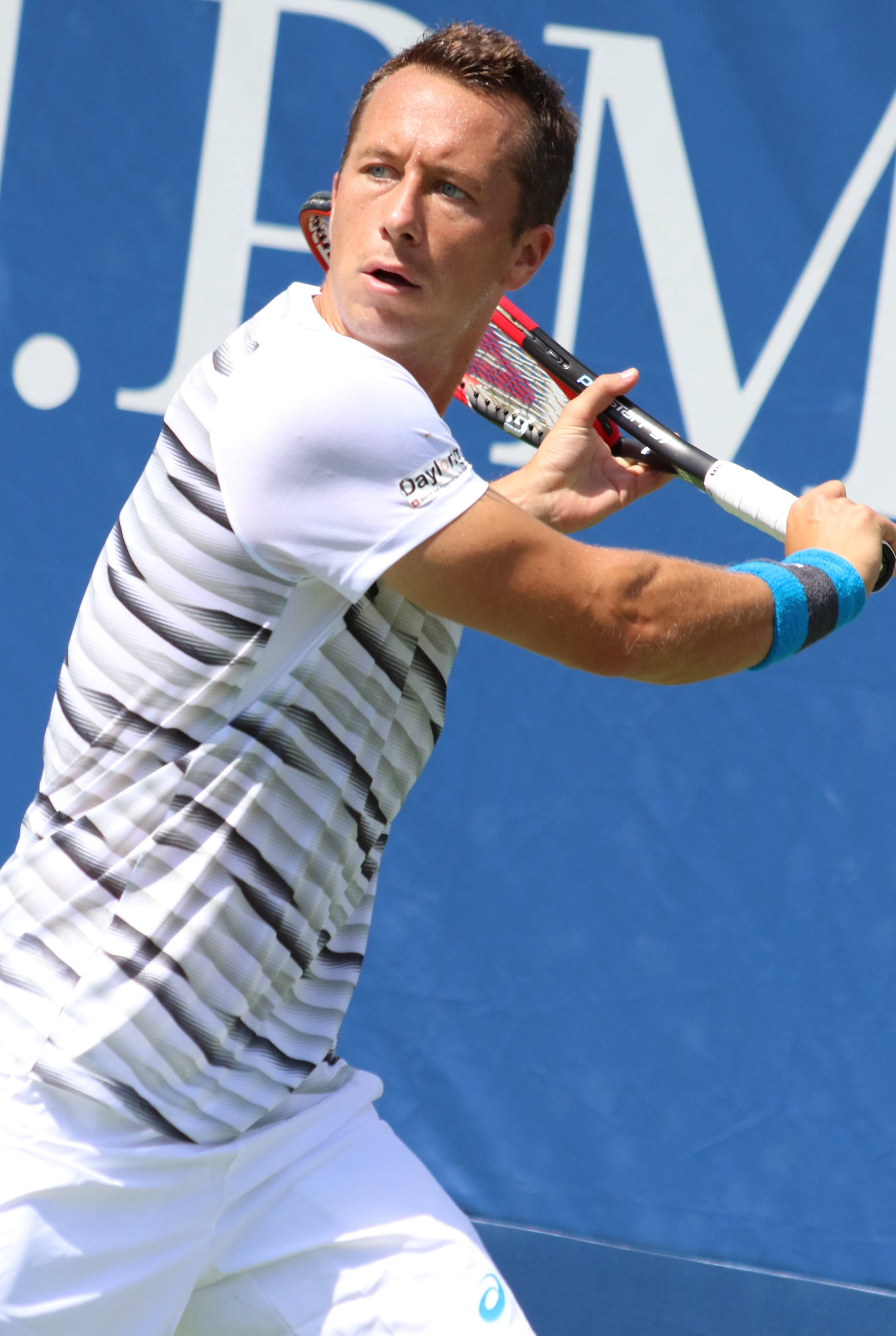 Tennis 桌布 壁紙 — 一位身穿白色條紋的男網球運動員，在藍色牆壁背景下，專注地揮動球拍。