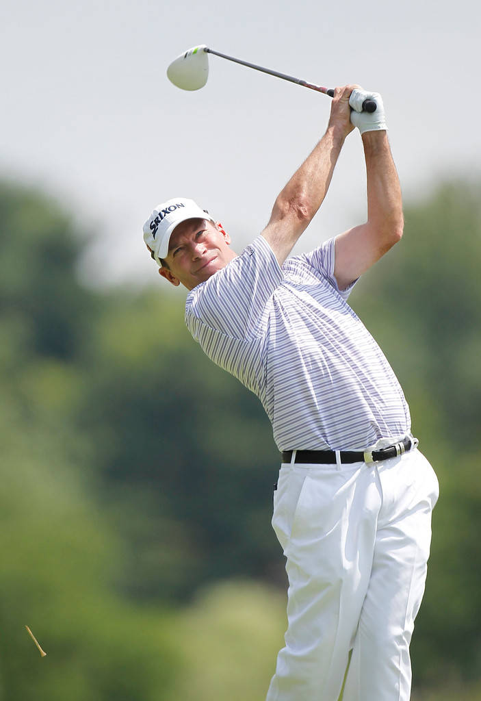 Golf Phone 桌布 壁紙 — 一位身穿白色條紋襯衫和帽子的男性高爾夫球手，在模糊的綠色背景下專注地揮桿。