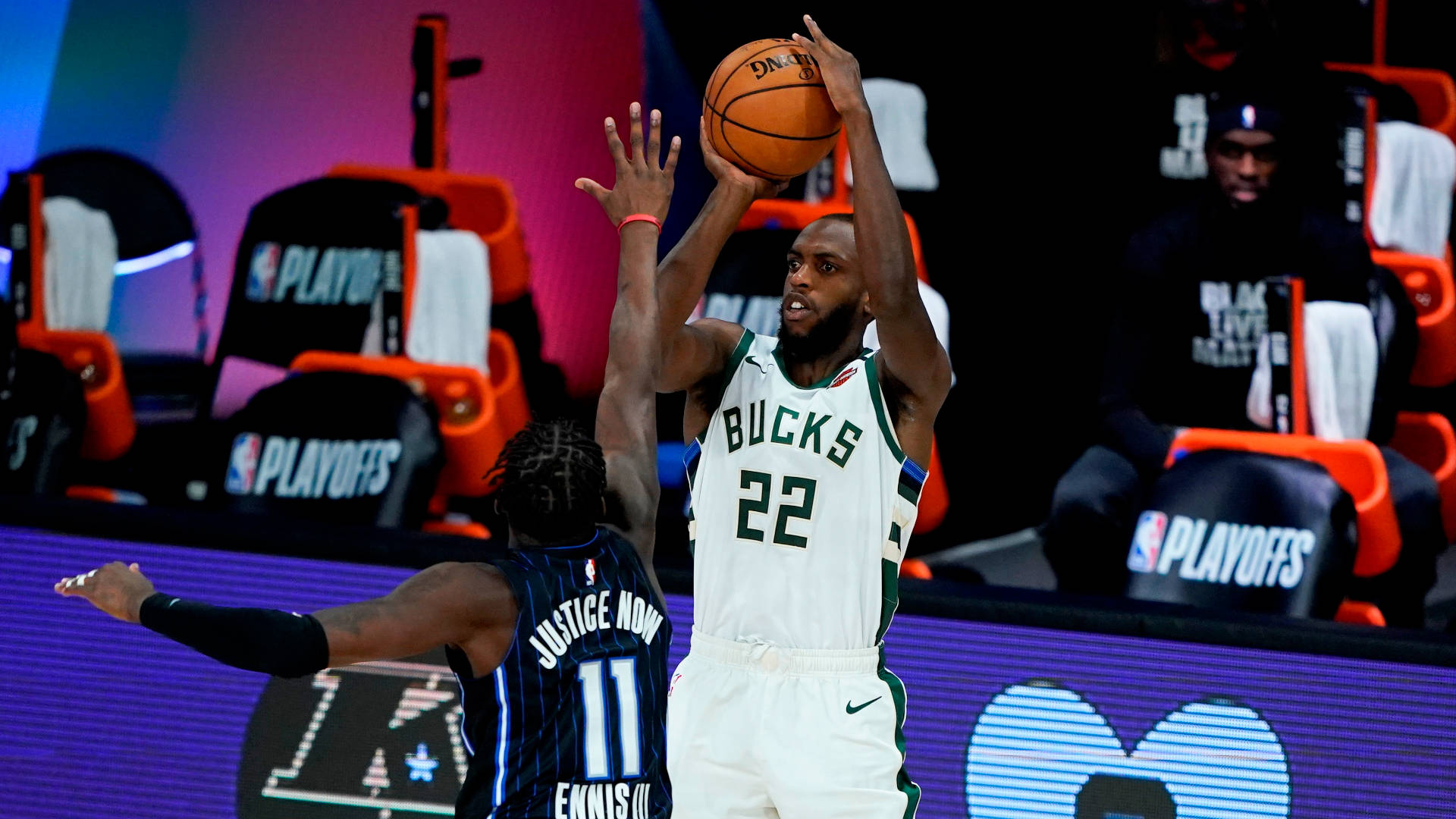 Khris Middleton 桌布 壁紙 — 一位身穿白色球衣22號的密爾瓦基公鹿球員在NBA季後賽比賽中投籃，同時被一位身穿深色球衣的奧蘭多魔術球員防守。