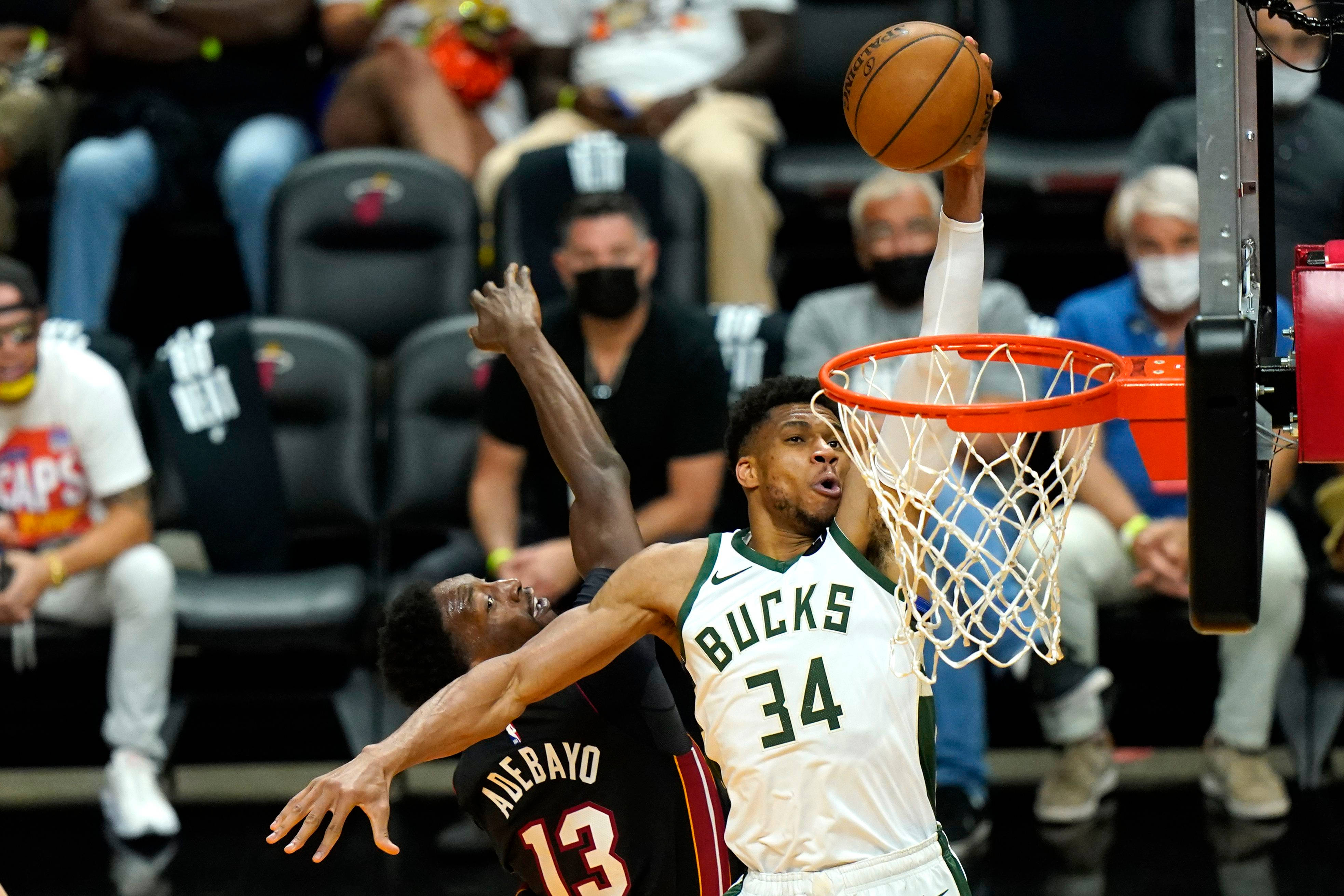 Giannis 桌布 壁紙 — 一位身穿白色球衣的密爾瓦基公鹿球員灌籃，而一位身穿黑色球衣的邁阿密熱火防守球員試圖封阻。