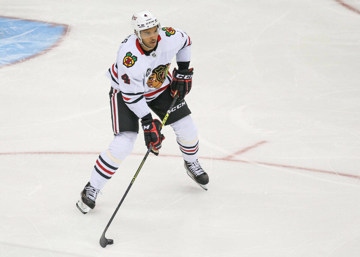 hockey 桌布 壁紙 — 一位身穿白色球衣的芝加哥黑鷹冰球球員手持球桿在冰上激烈滑行。