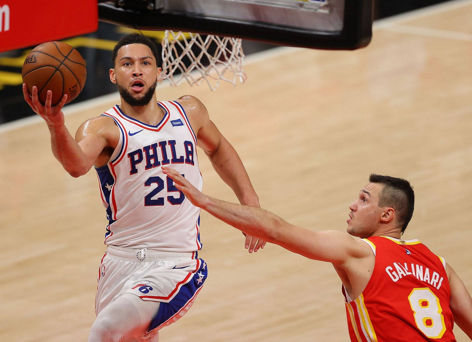 76ers 桌布 壁紙 — 一位身穿白色球衣的費城76人球員跳向籃框，而一位身穿紅色球衣的防守者伸手試圖封阻他的投籃。