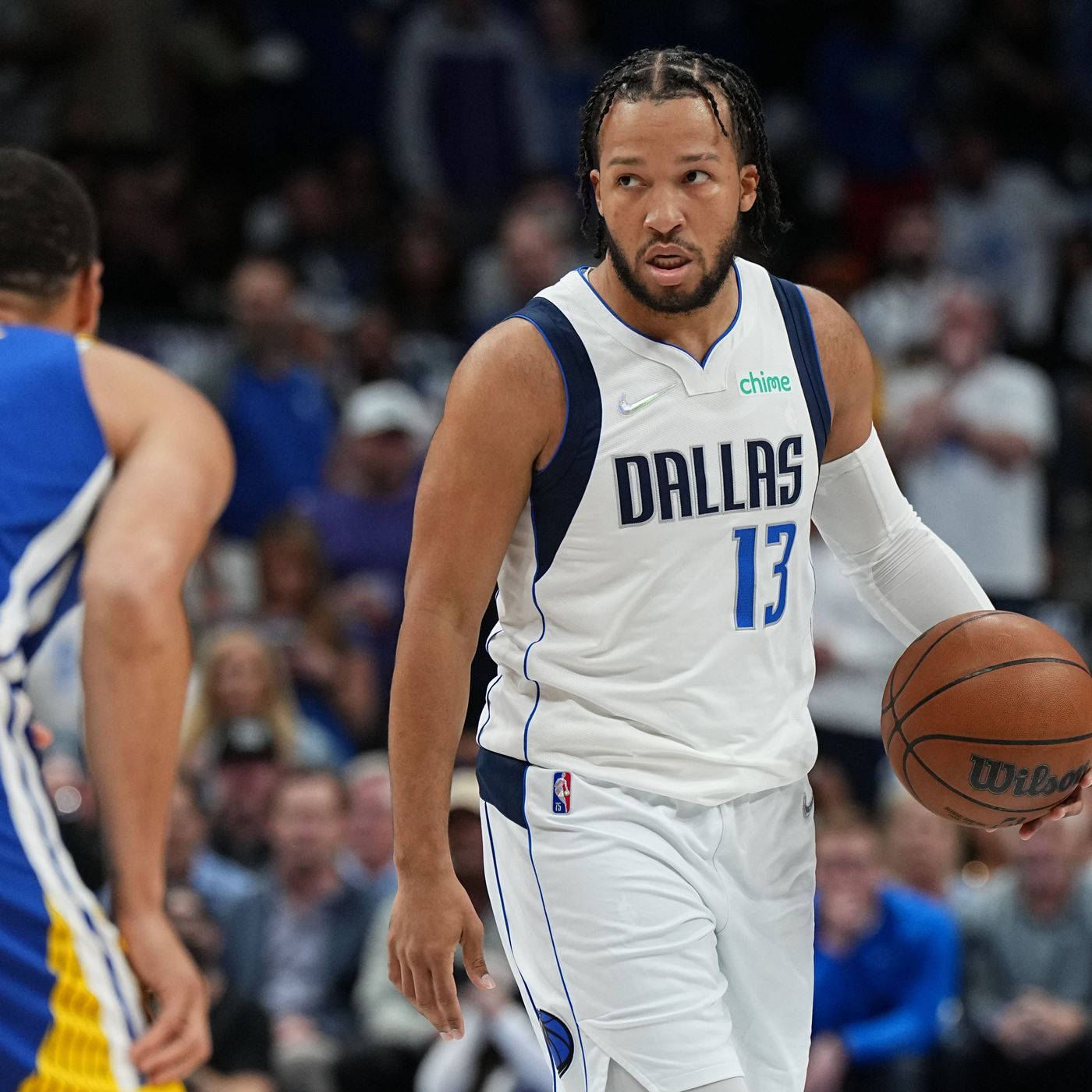 NBA 桌布 壁紙 — 一位身穿白色球衣的達拉斯獨行俠籃球運動員在激烈的比賽中運球，背景是模糊的人群。