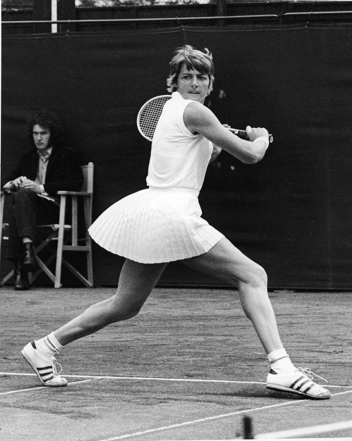 運動 桌布 壁紙 — 一位身穿白色百褶裙和Adidas鞋的女網球選手在紅土球場上揮拍擊球。
