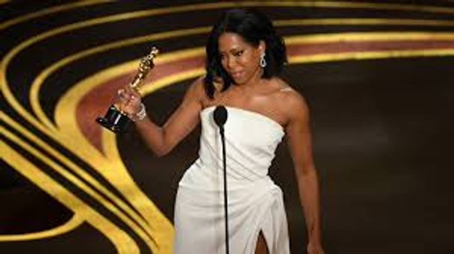 Celebrity 桌布 壁紙 — 一位身穿白色禮服的女性在金色舞台上，身後有旋轉圖案，手持奧斯卡獎座。
