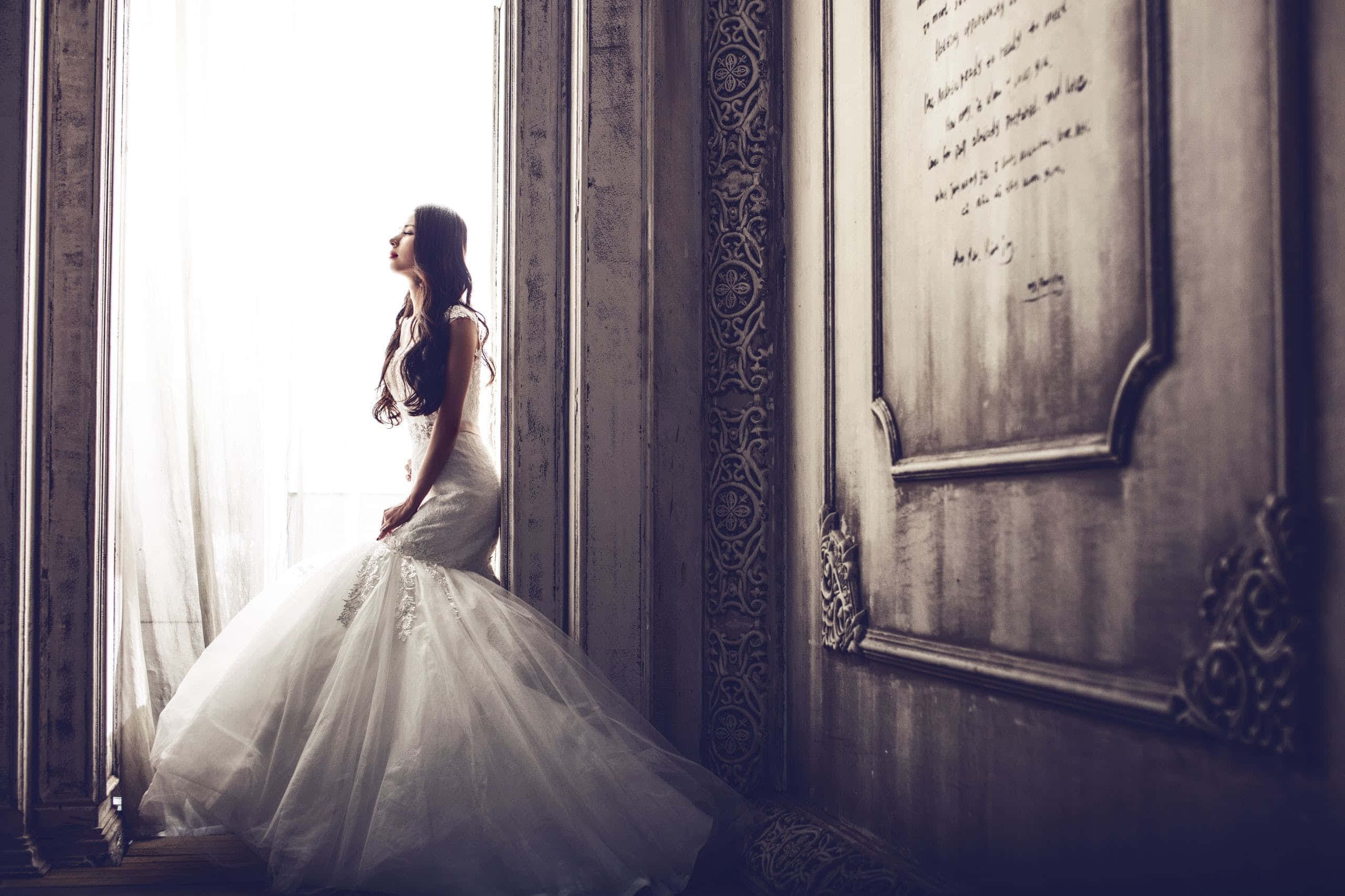 Bride 桌布 壁紙 — 一位身穿白色禮服的新娘坐在華麗房間的陽光窗邊，靜靜地向上凝視，帶著寧靜的沉思。