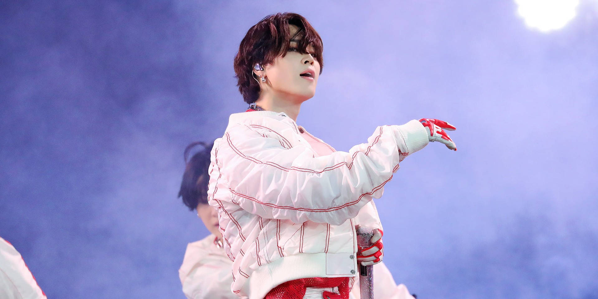 BTS 智旻 桌布 壁紙 — 一位身穿白色紅邊外套和手套的表演者，在煙霧瀰漫的藍色燈光舞台上熱情地做手勢。