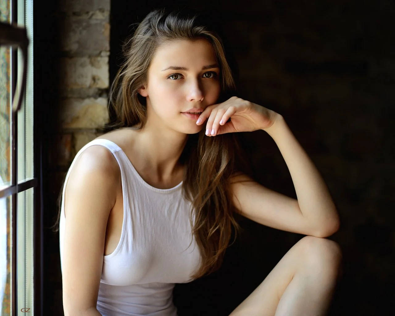 Pretty Woman 桌布 壁紙 — 一位身穿白色背心的年輕女性坐在磚牆窗邊，手放在下巴附近，沐浴在柔和自然光中。
