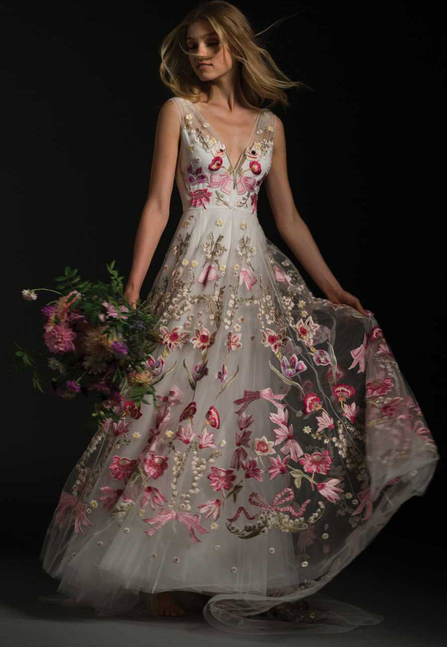 Bride 桌布 壁紙 — 一位身穿白色花卉長裙的女性，在柔和燈光下，手持花束，背景為黑色。