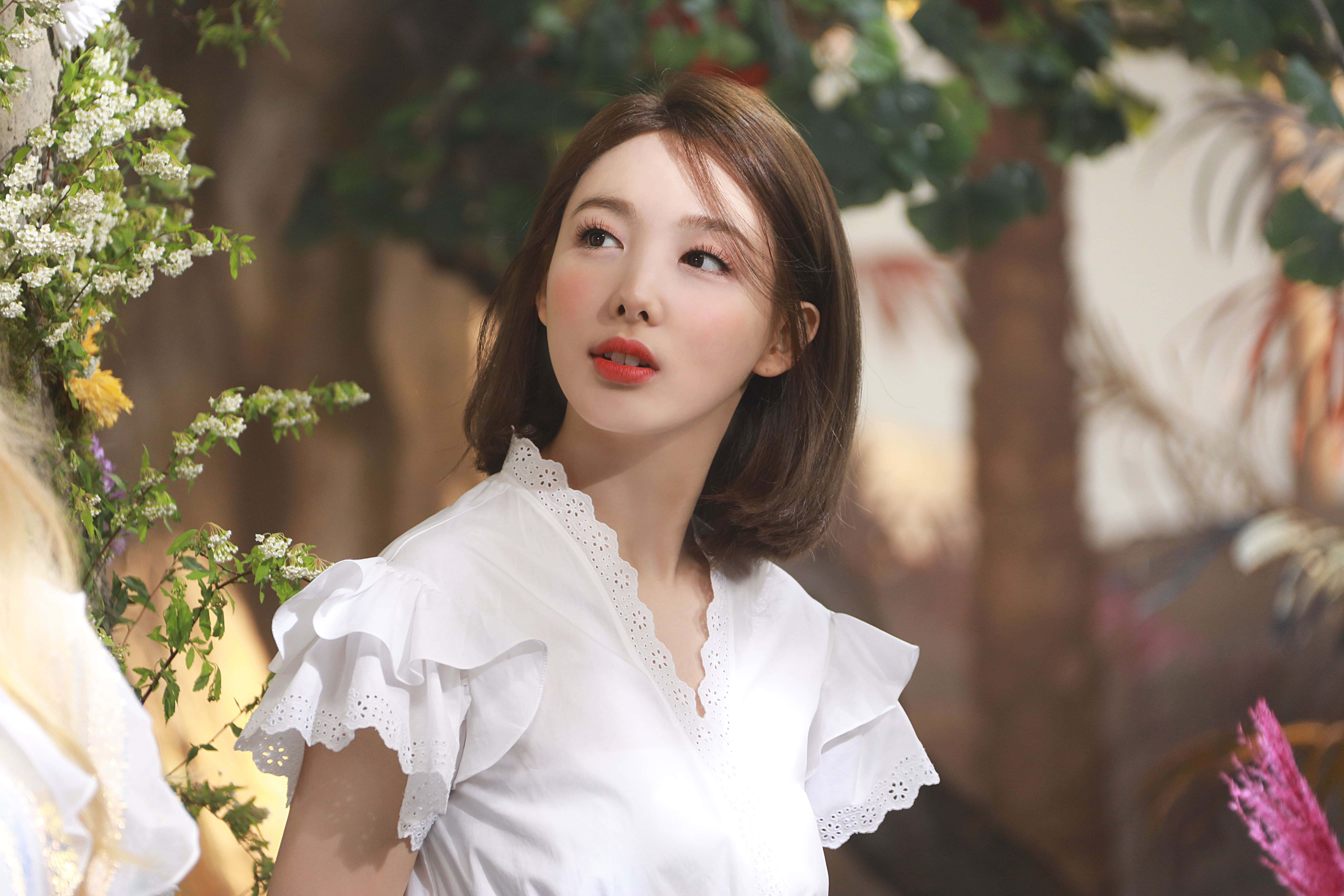 twice 桌布 壁紙 — 一位身穿白色荷葉邊襯衫的女性，在茂密的綠植和盛開的花朵中向上凝視。