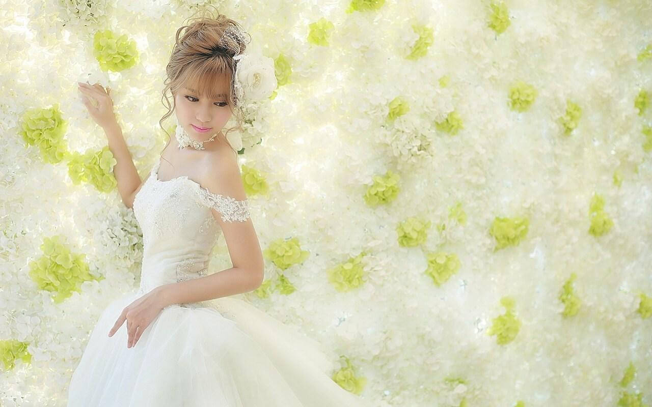 Bride 桌布 壁紙 — 一位身穿白色蕾絲婚紗的新娘，在白色和淺綠色繡球花牆前優雅地擺姿勢。