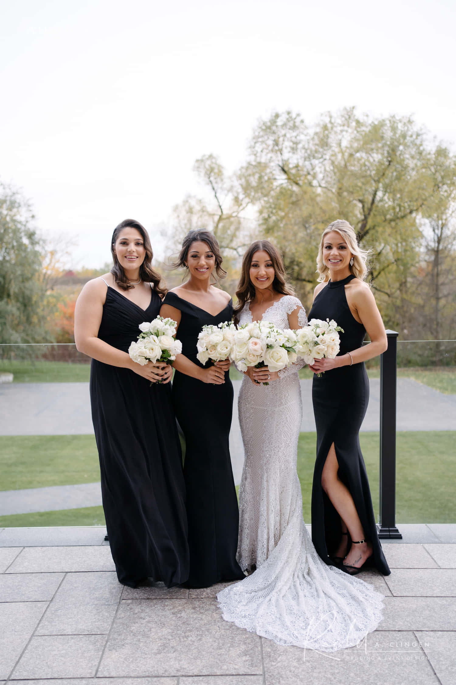 Black And White Wedding 桌布 壁紙 — 一位身穿白色蕾絲禮服的新娘與三位身穿黑色禮服的伴娘在戶外手持白色花束。
