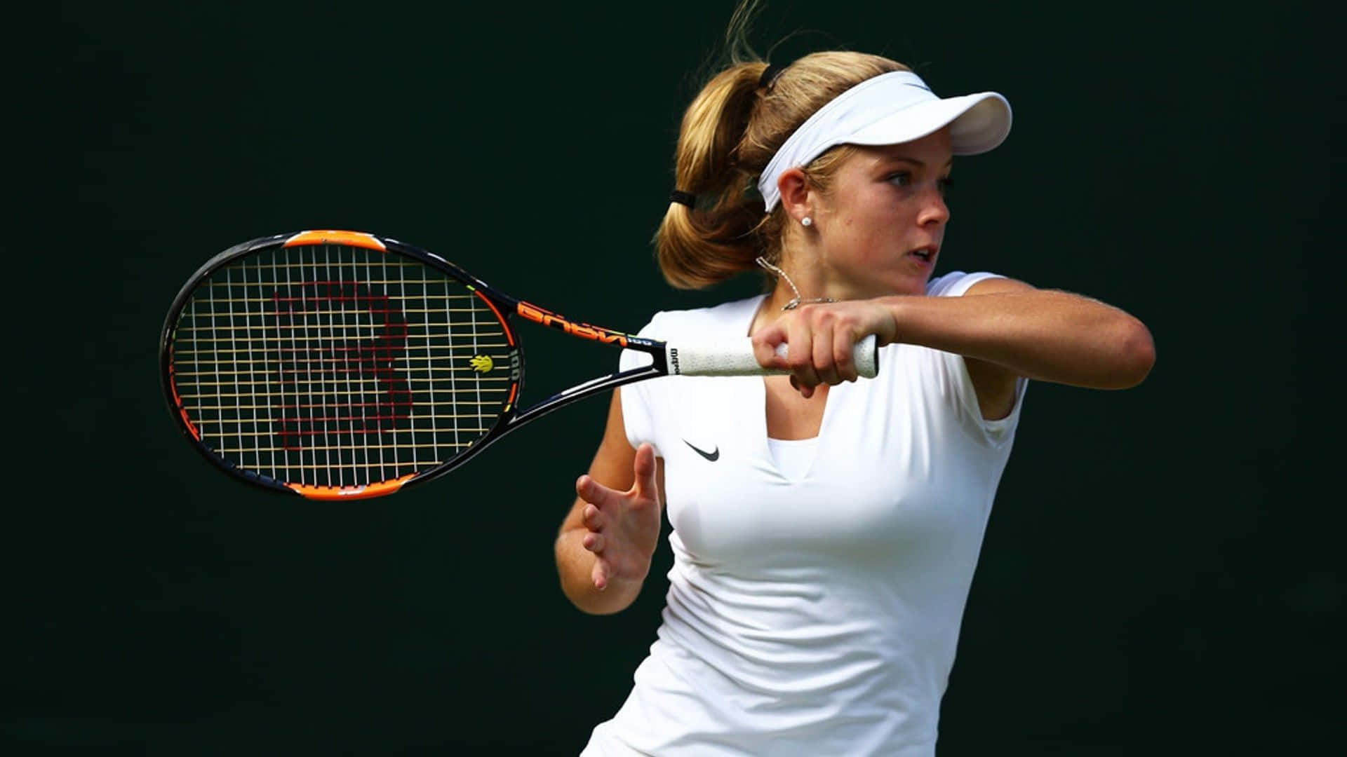 Athlete 桌布 壁紙 — 一位身穿白色裝備的女網球運動員，在深綠色背景下專注地揮拍。