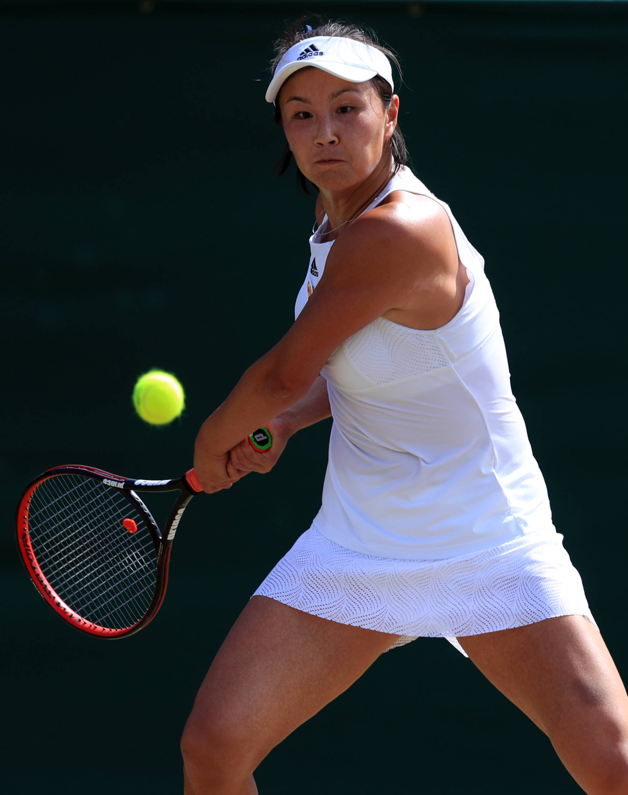Tennis 桌布 壁紙 — 一位身穿白色裝備的女網球運動員在深綠色背景下揮拍擊打一個亮黃色的球。