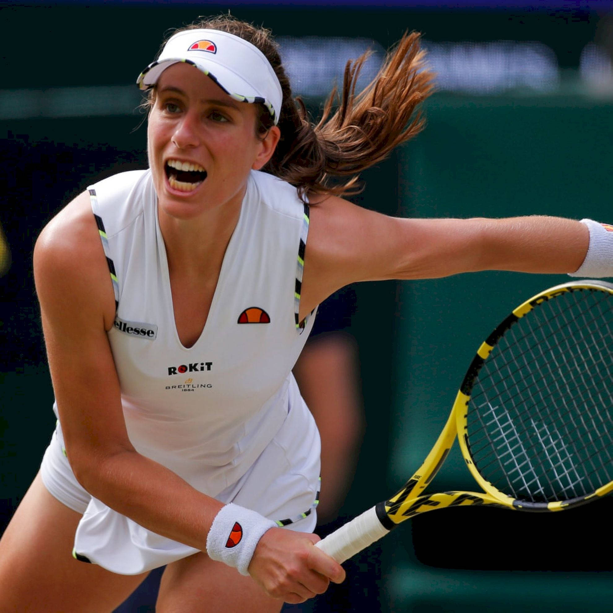 Athletic 桌布 壁紙 — 一位身穿白色裝備的女網球選手在草地場上揮拍時發出強烈的吼叫。