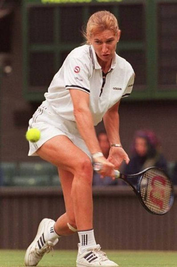 Tennis 桌布 壁紙 — 一位身穿白色裝備的女網球選手在草地場上向前猛衝，用球拍擊打一個亮黃色的球。