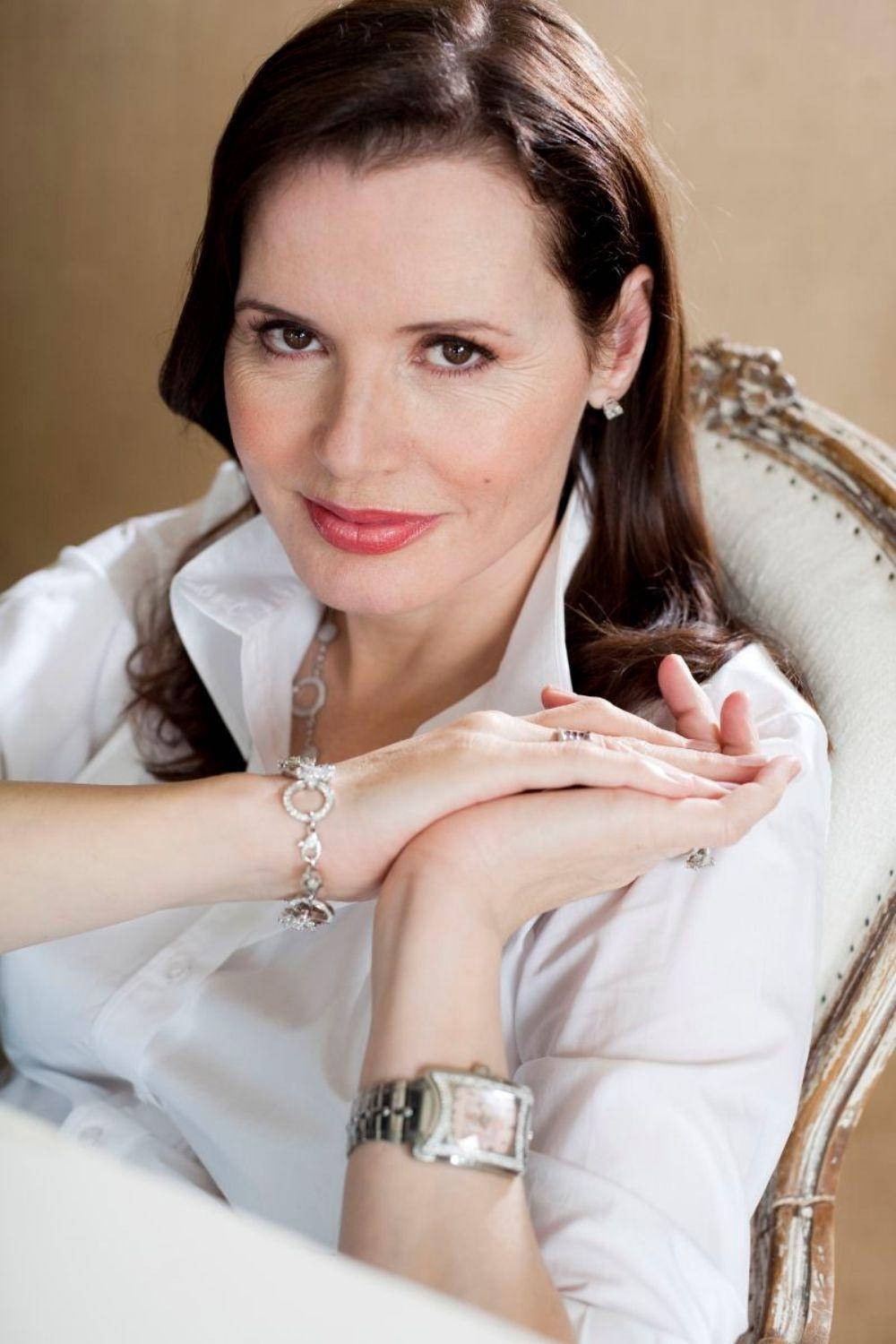 Celebrity 桌布 壁紙 — 一位身穿白色襯衫的優雅女士優雅地坐在復古椅子上，佩戴珠寶，溫暖地凝視鏡頭。