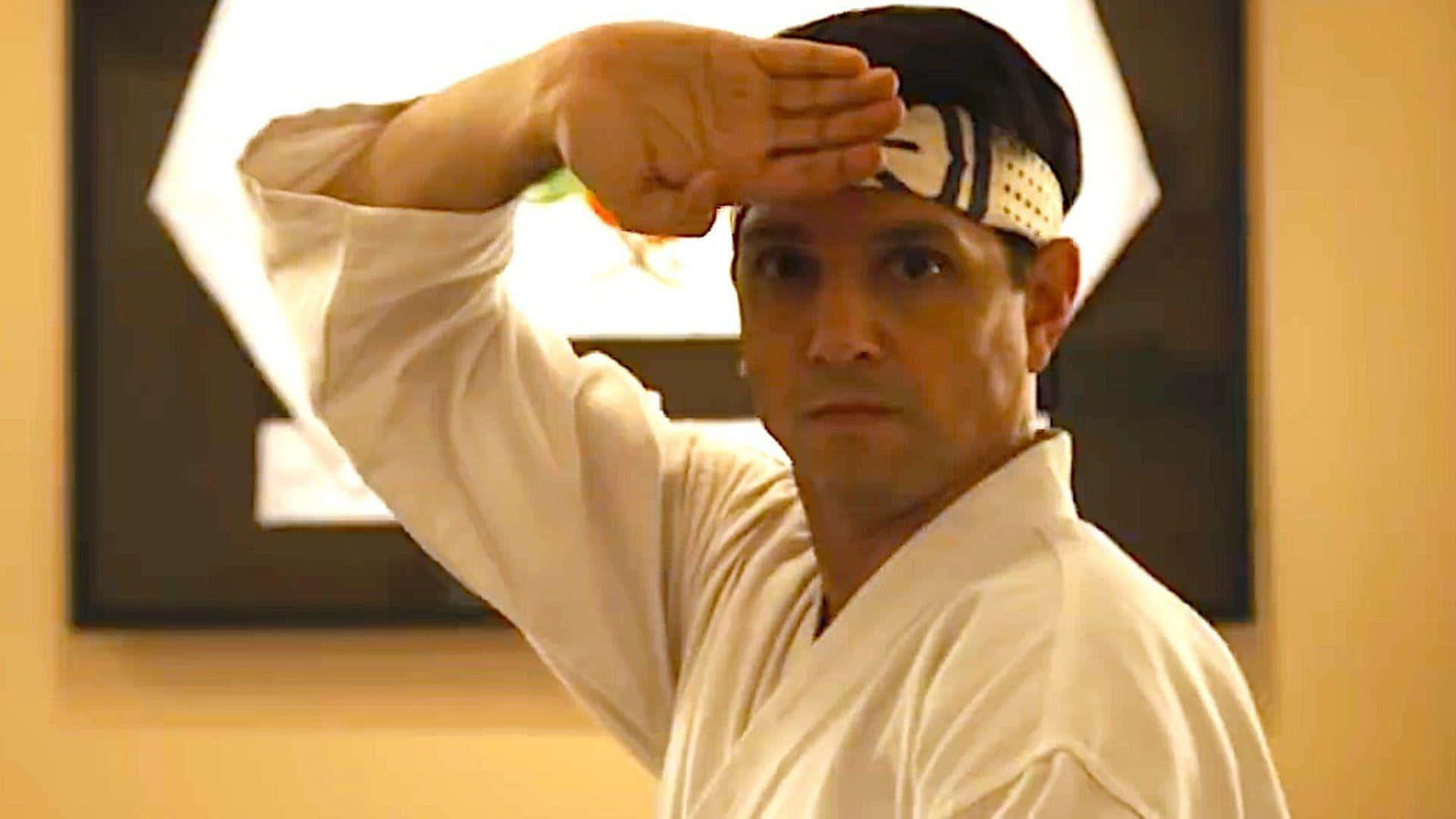 Ralph Macchio 桌布 壁紙 — 一位身穿白色道服和頭帶的武術家，以專注的表情遮擋眼睛免受強光照射。
