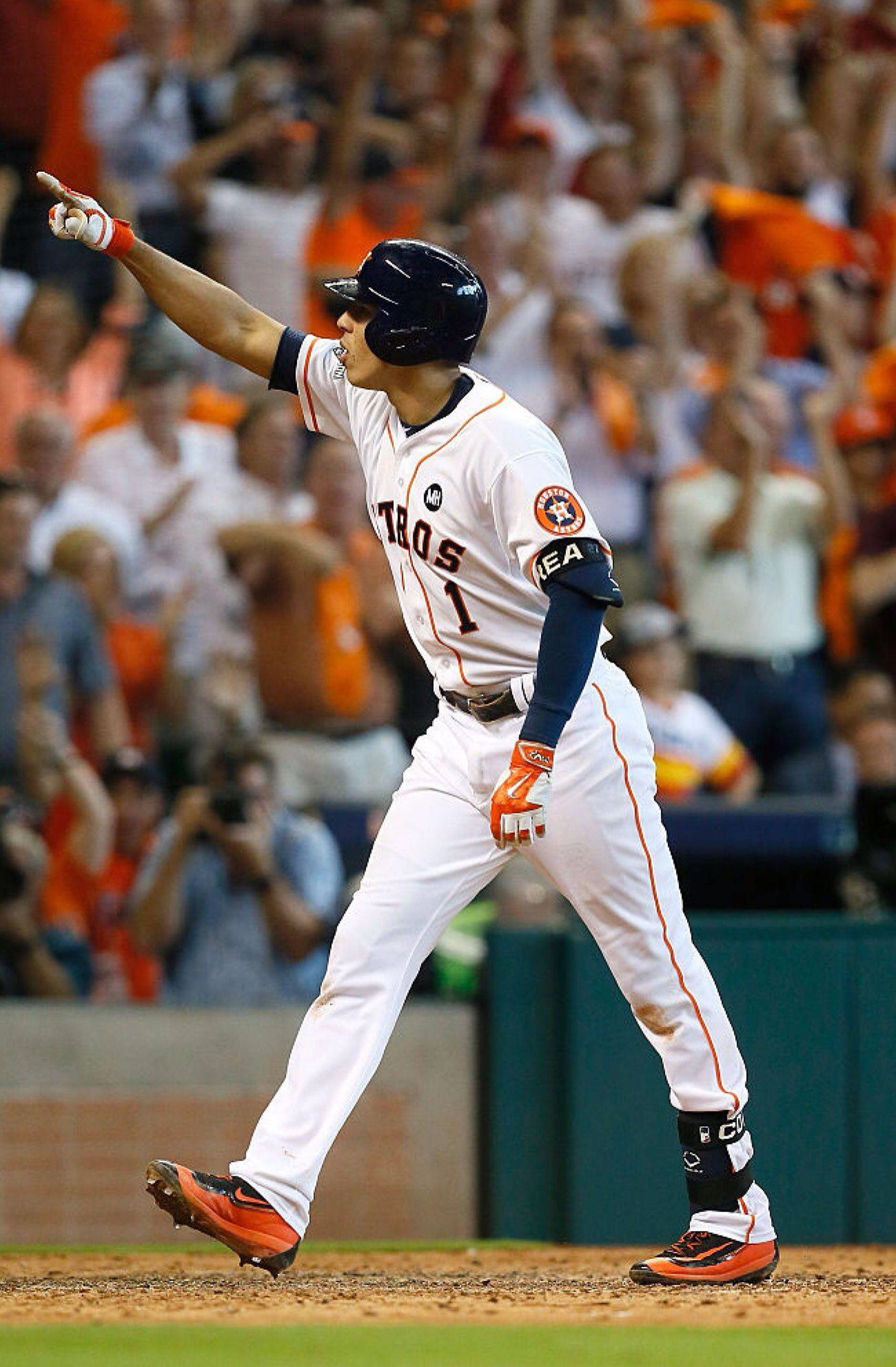Carlos Correa 桌布 壁紙 — 一位身穿白色配橙色點綴球衣的休士頓太空人棒球選手，在夜晚慶祝全壘打，身後有群眾歡呼。