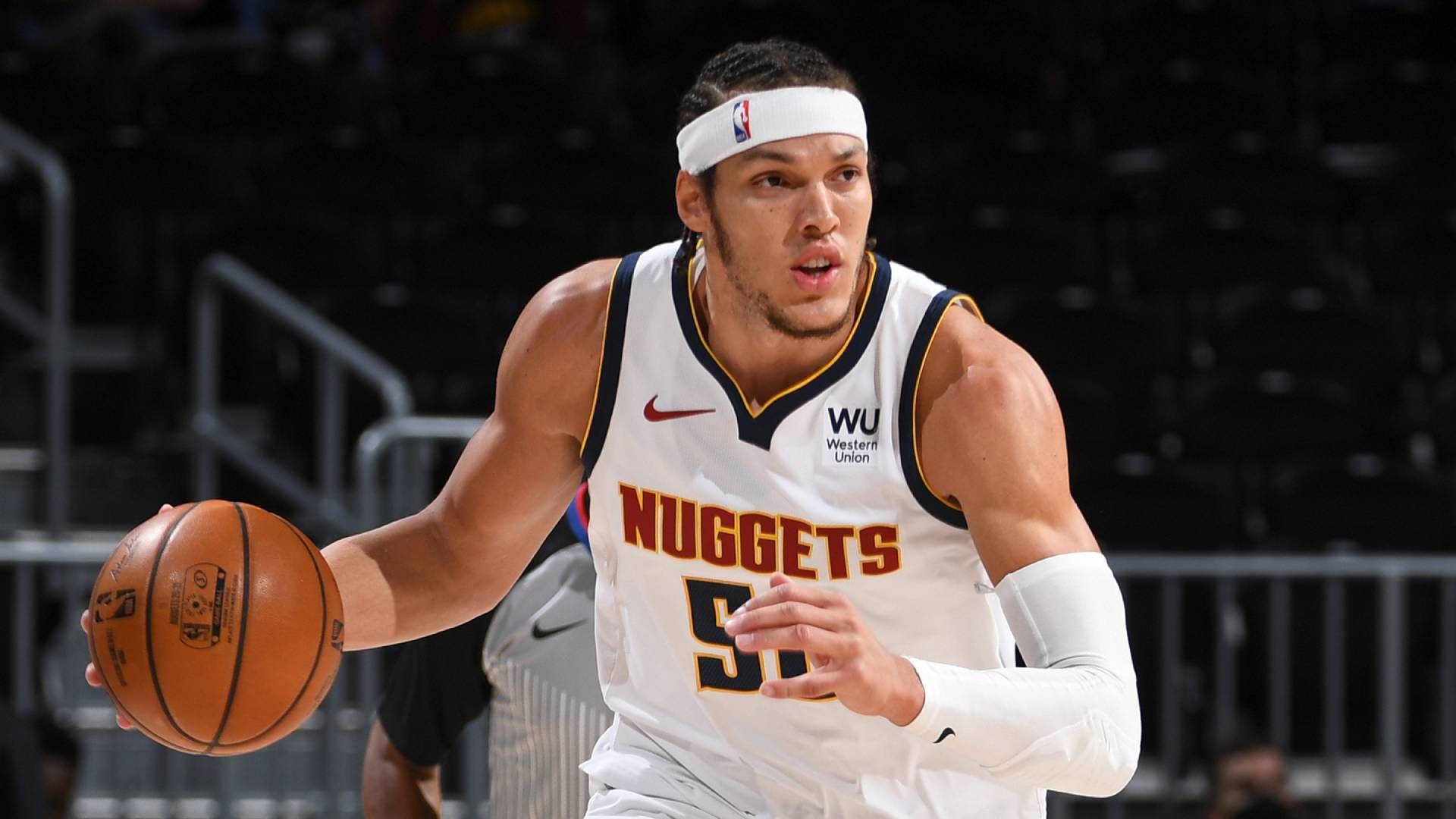 aaron gordon 桌布 壁紙 — 一位身穿白色金塊球衣的專注籃球運動員，在明亮的場館燈光下於激烈比賽中運球。