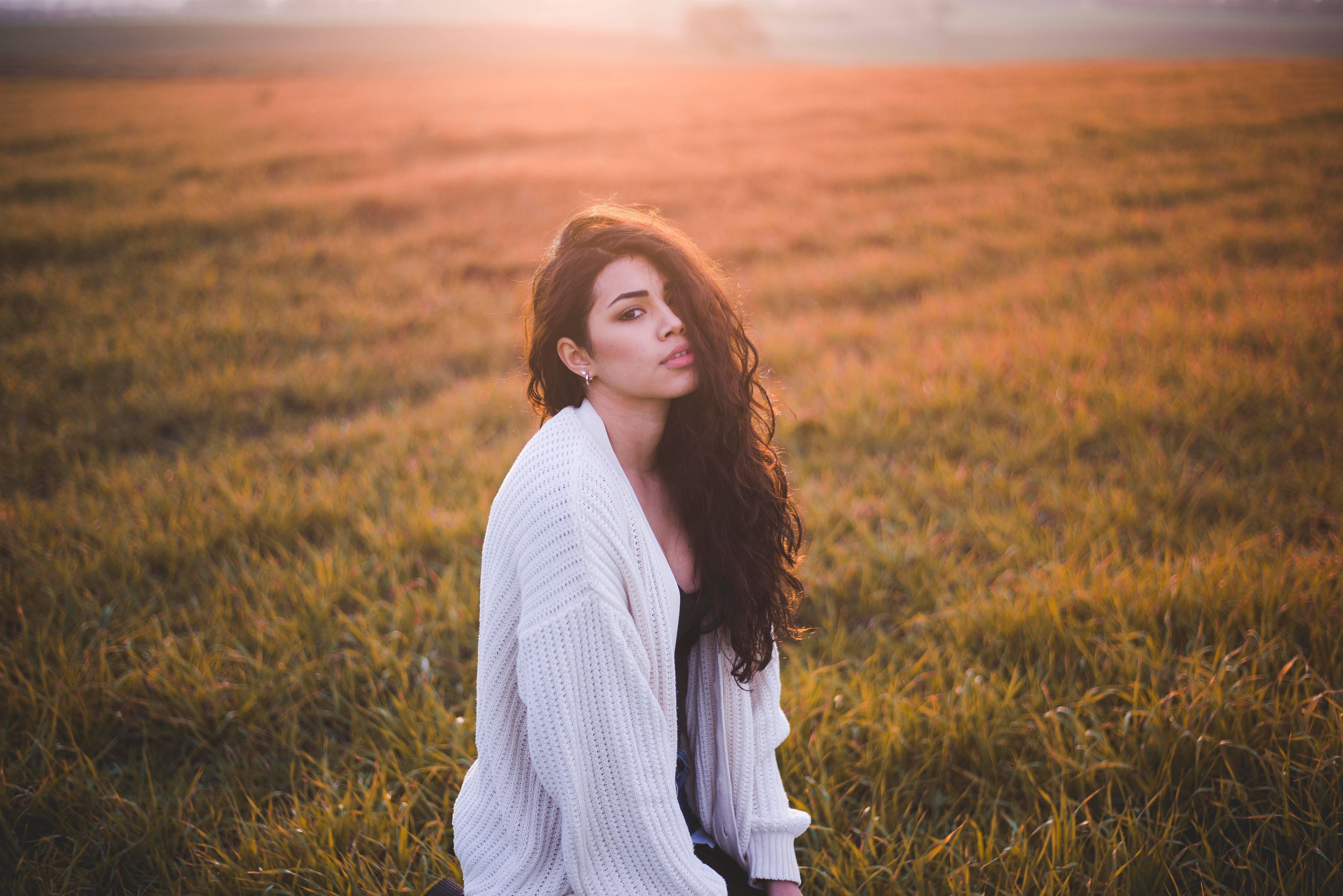 Grass 桌布 壁紙 — 一位身穿白色針織開襟衫的女子坐在沐浴在溫暖夕陽光下的金色田野中。
