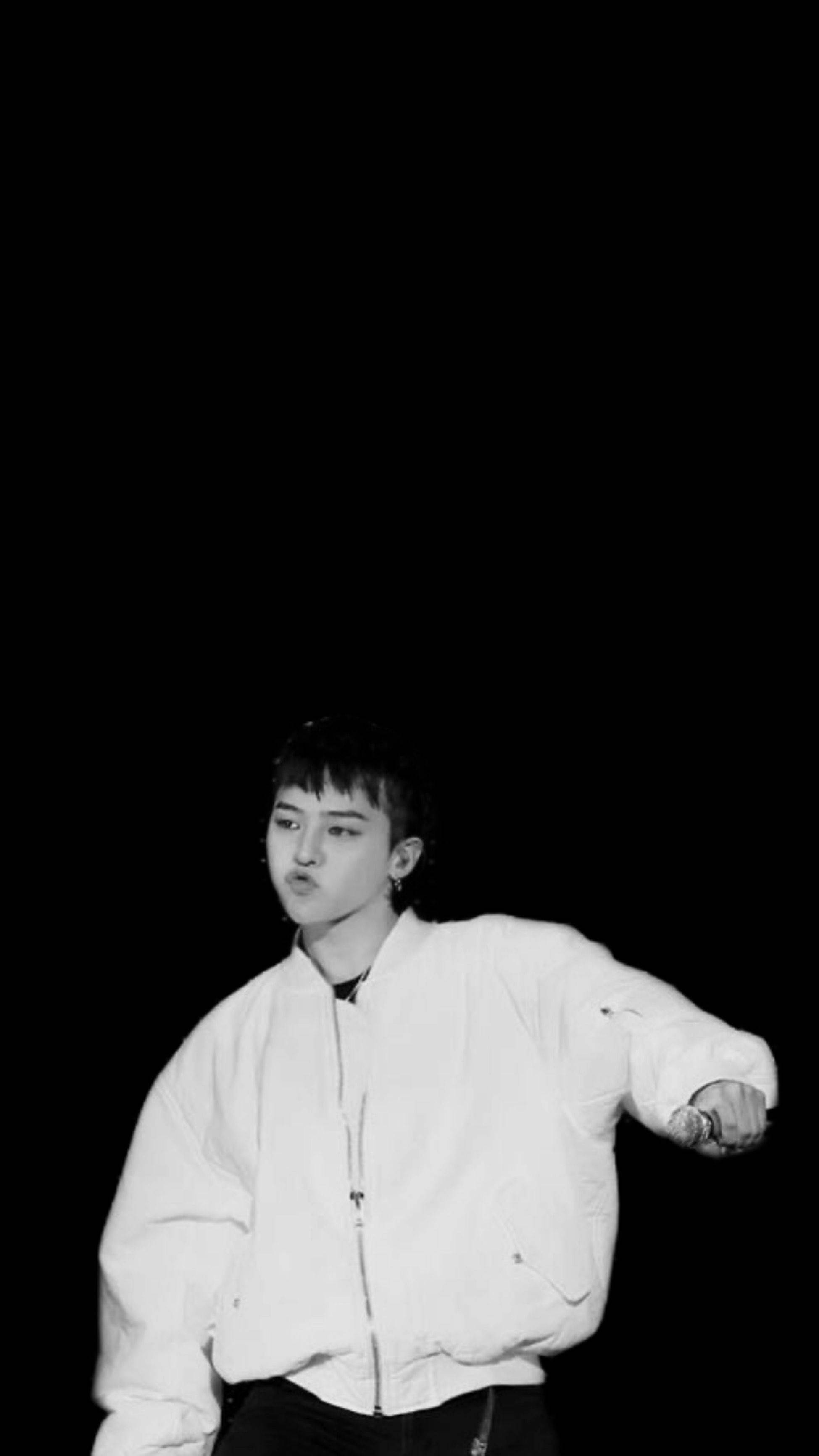 G-dragon 桌布 壁紙 — 一位身穿白色飛行員夾克的年輕男子，在單色黑色背景前自信地擺姿勢。