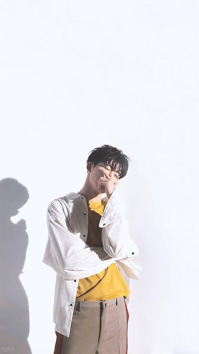 kim hanbin 桌布 壁紙 — 一位身穿白襯衫和黃色T恤的年輕男子在純白背景前頑皮地擺姿勢，身旁投射出強烈的陰影。