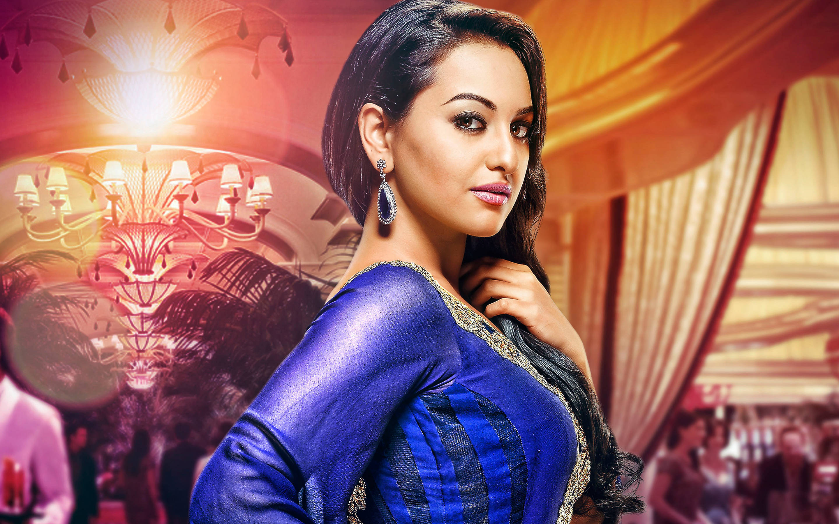 Sonakshi Sinha 桌布 壁紙 — 一位身穿皇家藍色紗麗的迷人女性，在豪華金色宴會廳閃爍的水晶燈下自信地擺姿勢。