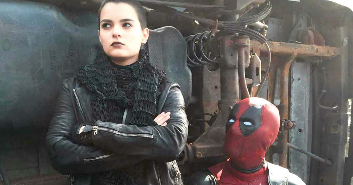 Deadpool And Negasonic Teenage Warhead 桌布 壁紙 — 一位身穿皮夾克的女性交叉雙臂，站在死侍旁邊，身處生鏽的車輛殘骸中。