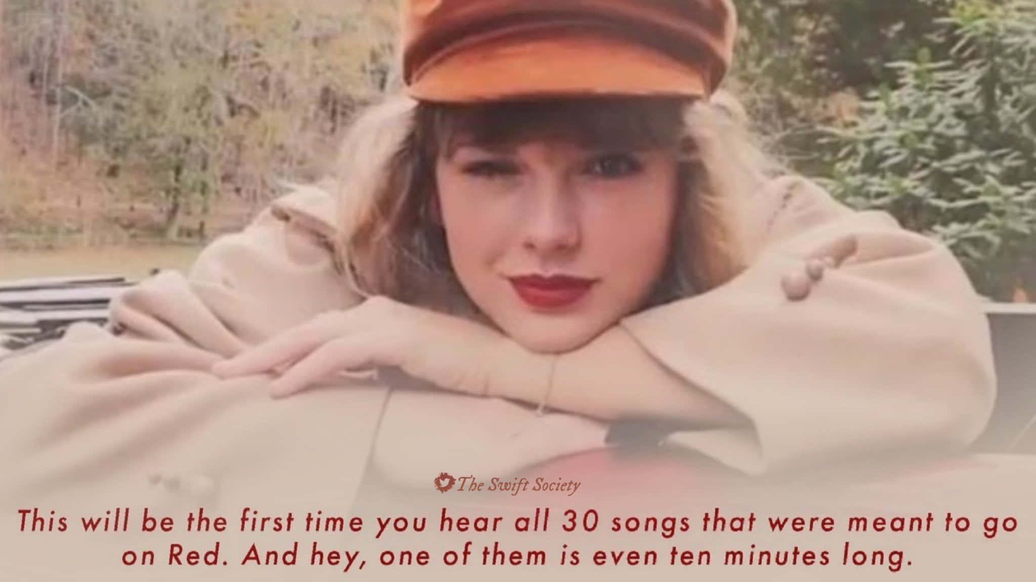 Taylor Swift Laptop 桌布 壁紙 — 一位身穿米色外套和橙色帽子的女士，在模糊的自然背景下，將下巴擱在手臂上，溫柔地凝視鏡頭。