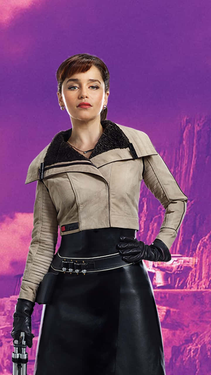 Solo A Star Wars Story 桌布 壁紙 — 一位身穿米色外套和黑色皮裙的女性自信地站在充滿活力的紫色外星人峽谷背景前。
