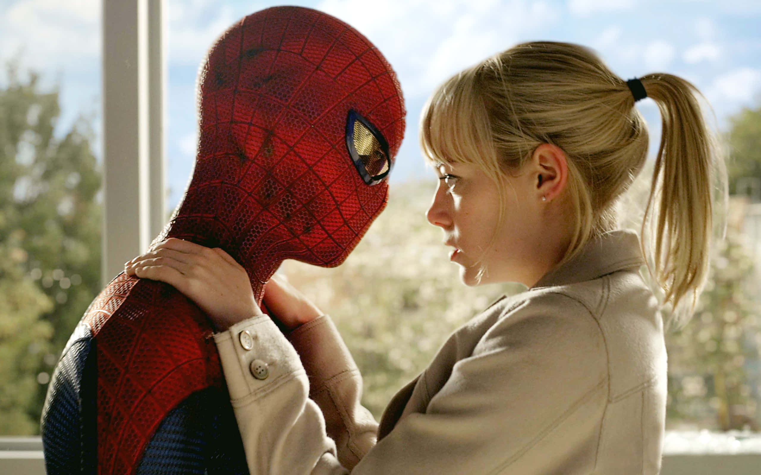 Gwen Stacy 桌布 壁紙 — 一位身穿米色外套的女性輕輕地扶著蜘蛛人的肩膀，他們在明亮的窗邊面對面。