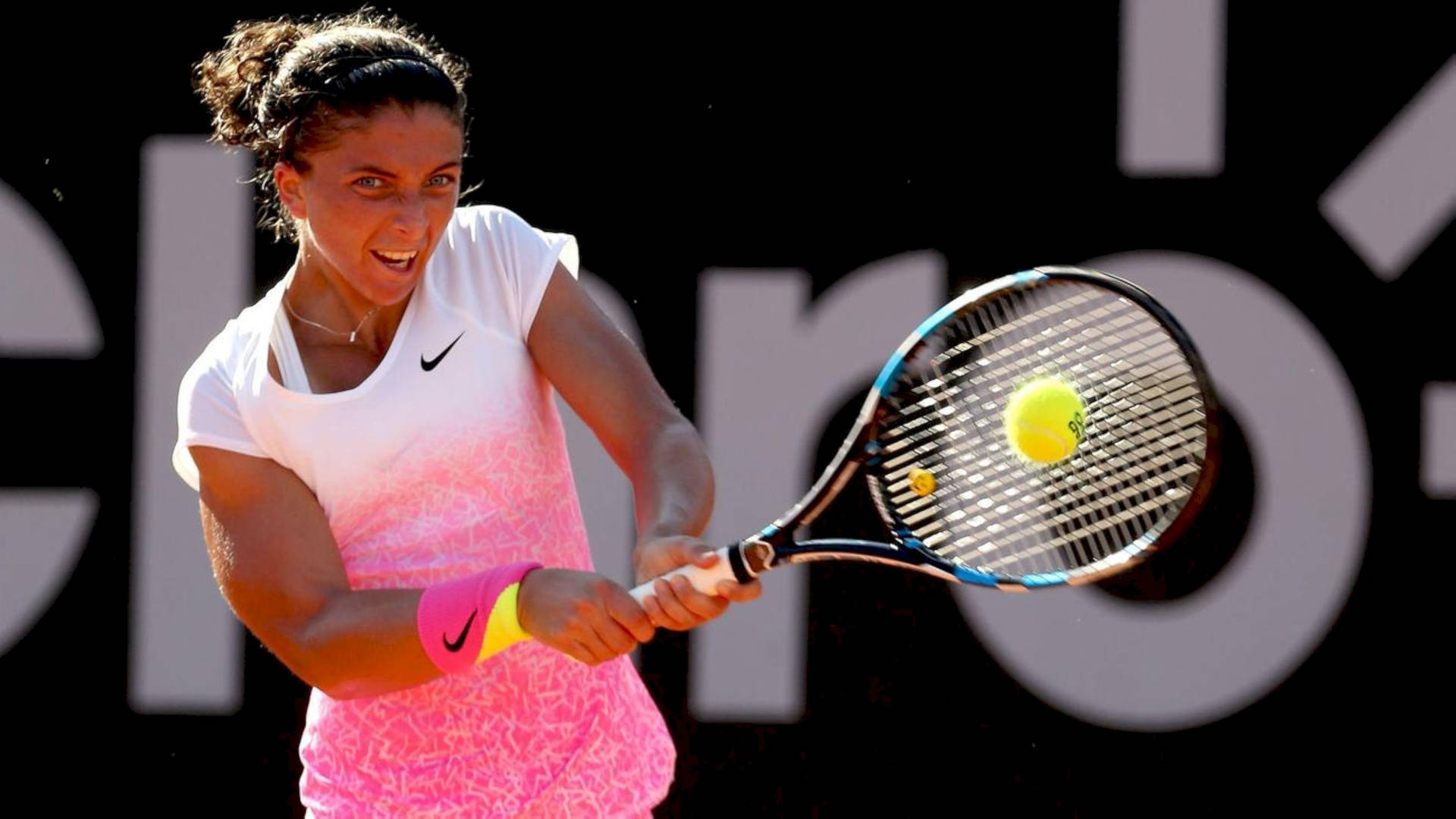 Nike 桌布 壁紙 — 一位身穿粉白色球衣的女網球選手，專注地揮拍擊打黃色網球。