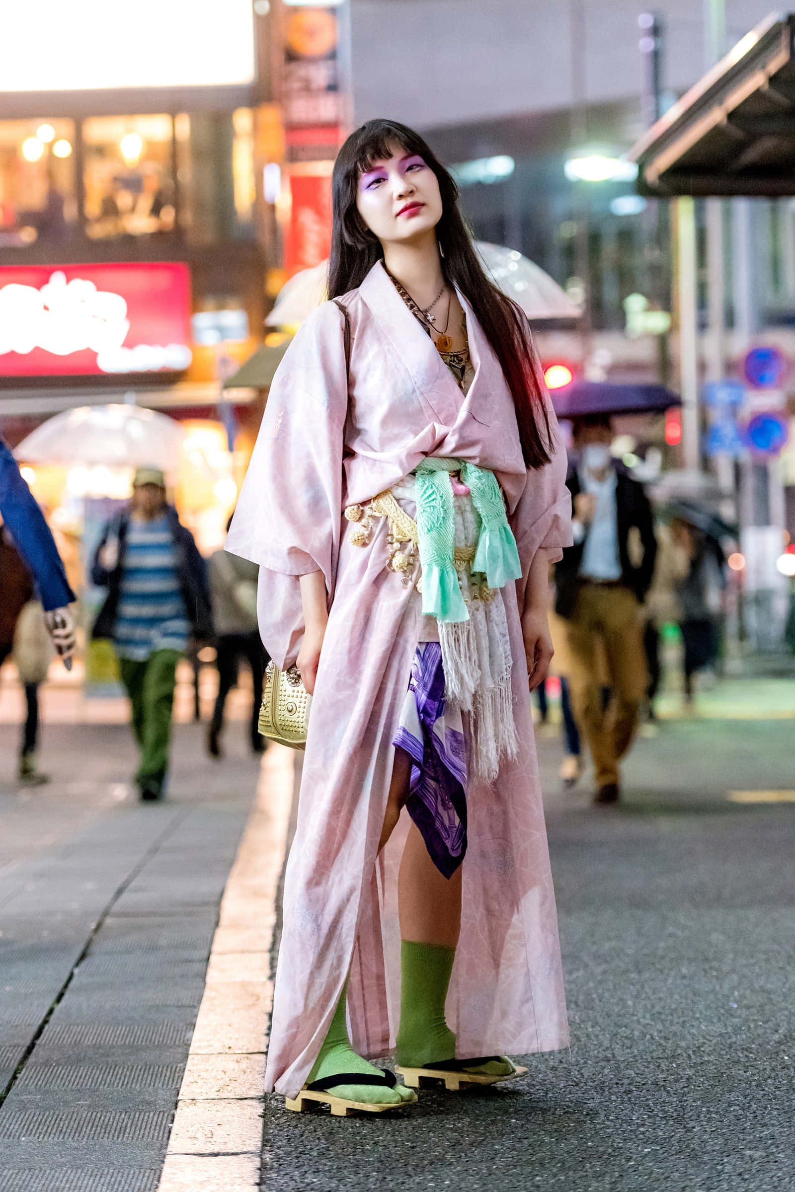 Kimono 桌布 壁紙 — 一位身穿粉紅色和服搭配綠色點綴的女性，自信地站在雨夜的東京街頭，周圍是閃爍的霓虹燈招牌和行人。