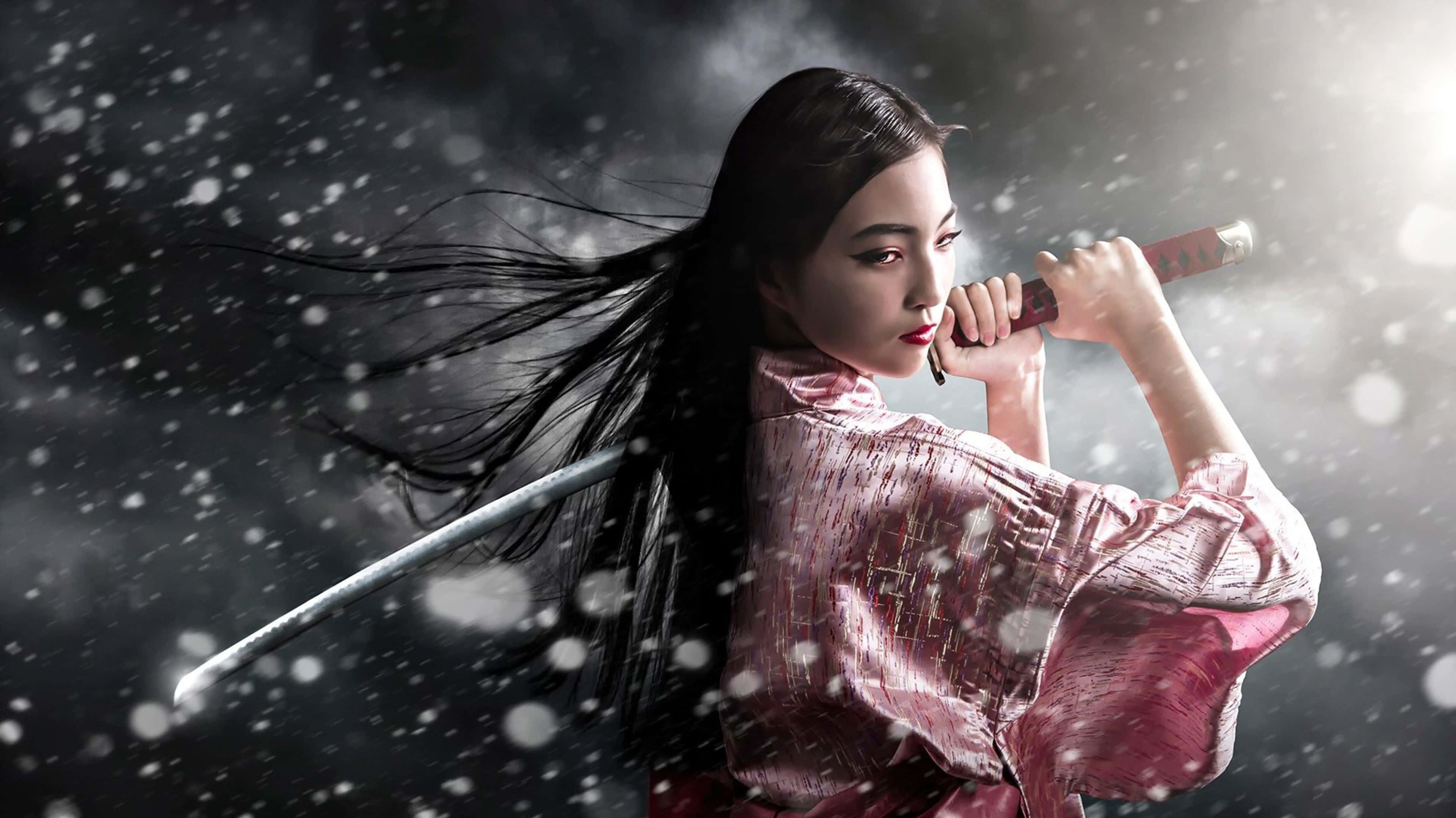 Female Samurai 桌布 壁紙 — 一位身穿粉紅色和服的優雅女武士在暴風雪中手持武士刀，雪花在她周圍旋轉。