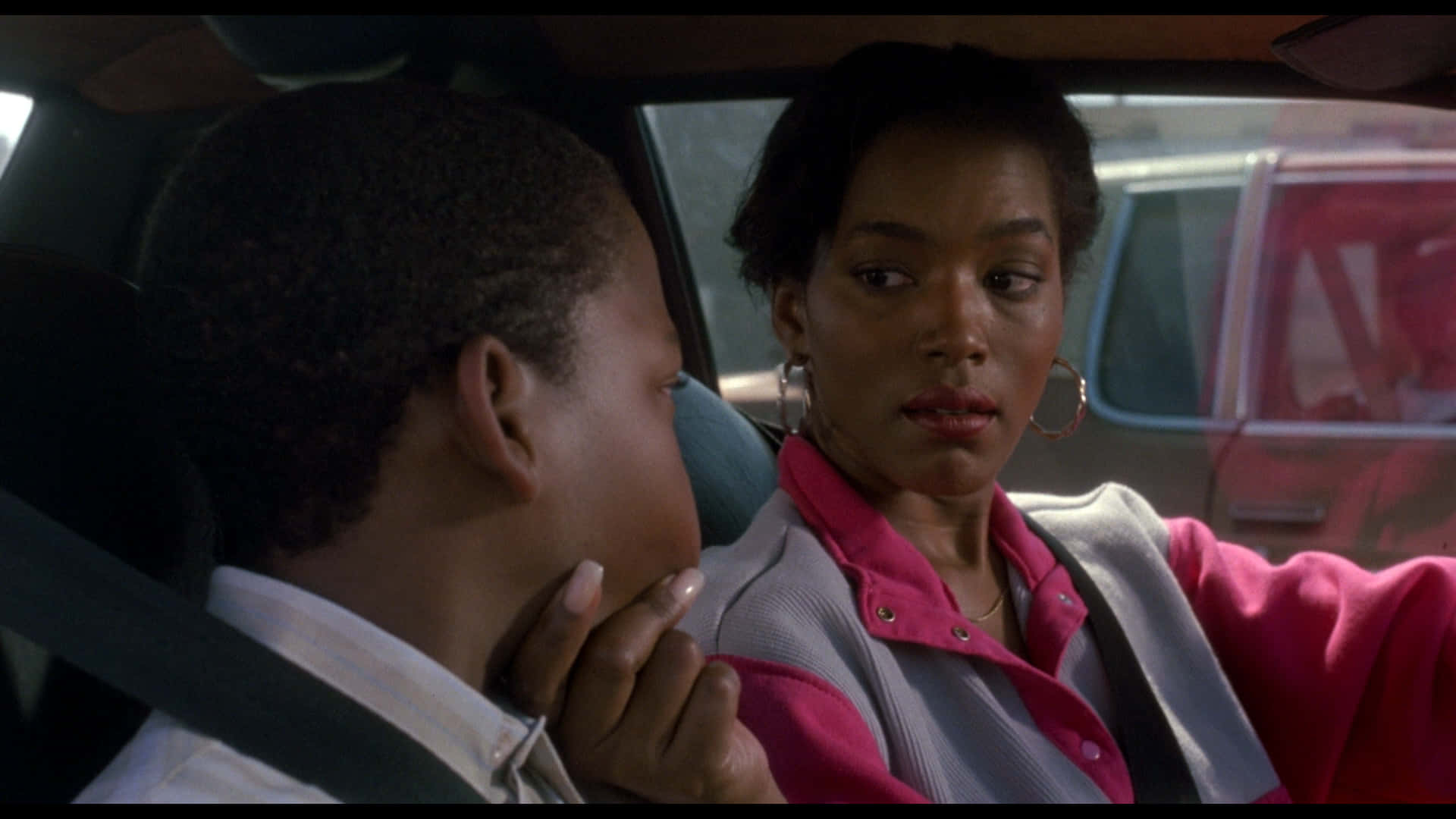 Boyz N The Hood 桌布 壁紙 — 一位身穿粉紅色外套的女性在車內輕柔地觸摸一個小男孩的臉頰，這是一個安靜的時刻。