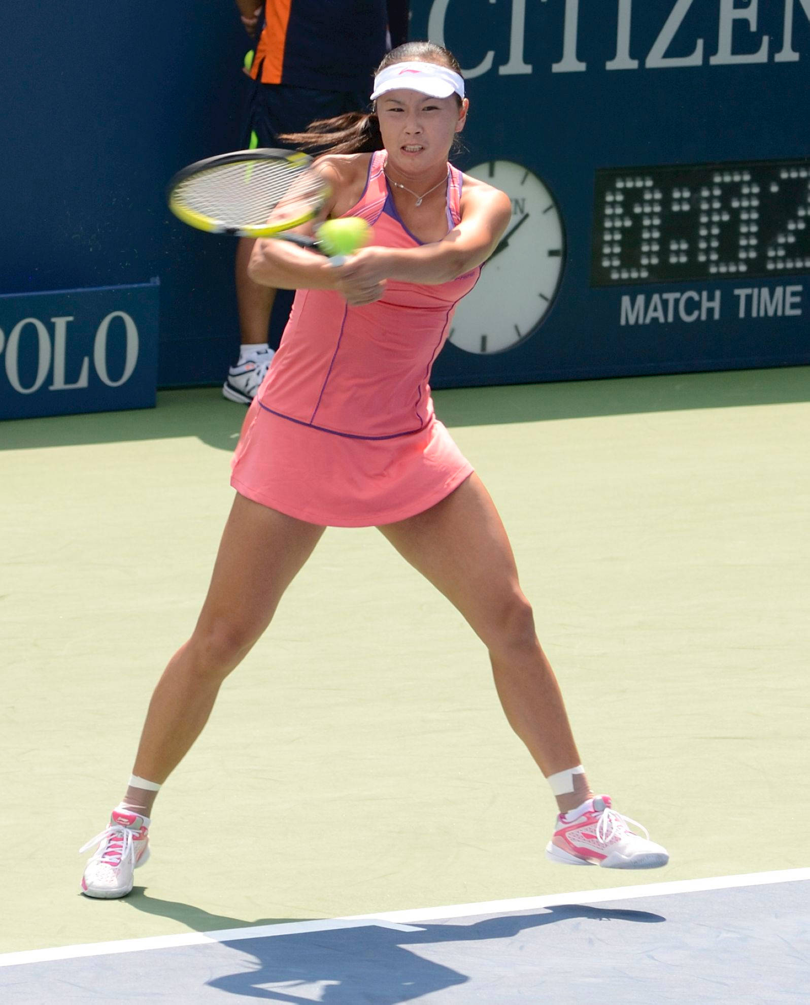 Tennis 桌布 壁紙 — 一位身穿粉紅色服裝的女網球選手在明亮的陽光下，於綠色球場上揮拍擊打黃色球。